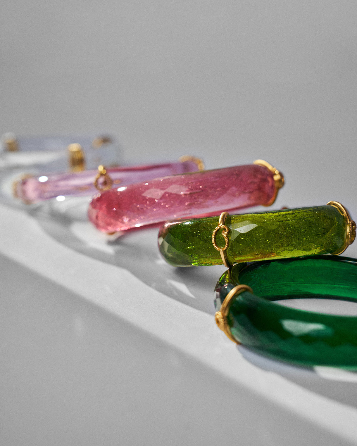 Close-up of translucent green and pink Baraat bangles with gold wraps.