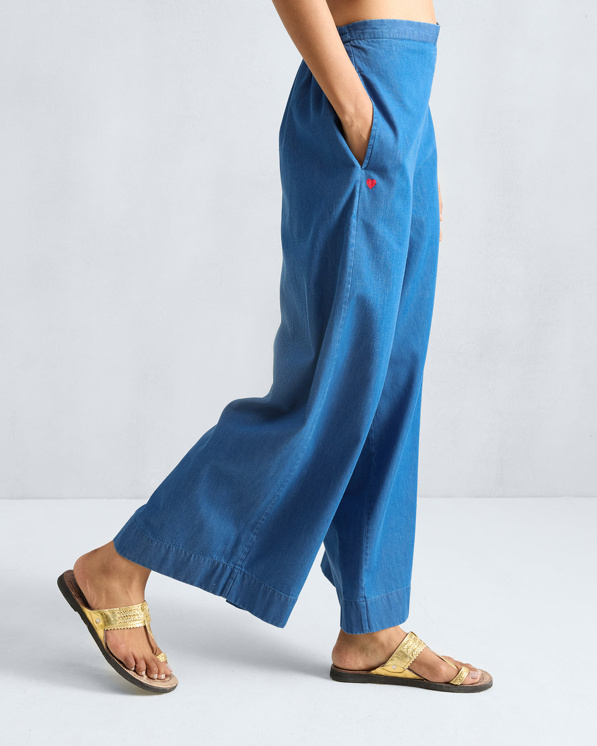 Side view of denim blue Basic pyjamas with a red heart by the pocket.