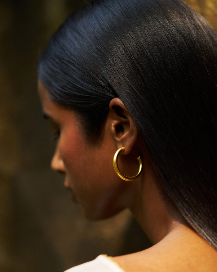 Side profile of gold Everyday Hoops worn on a person.