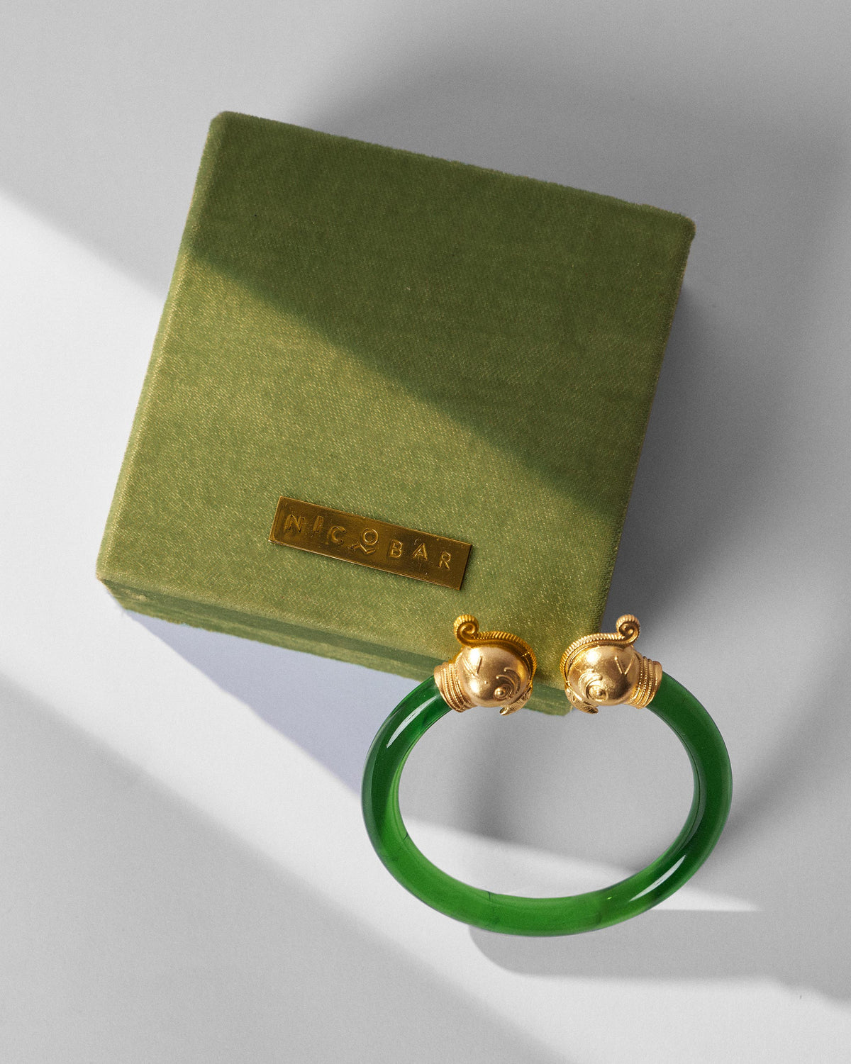 Green Mithu bangle beside an olive Nicobar jewellery box.
