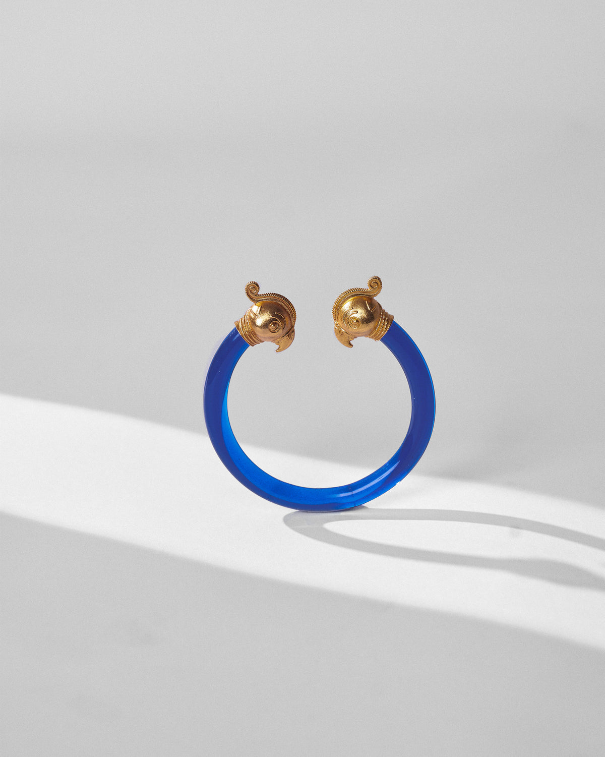 Blue Mithu Bangle with gold end pieces on a light surface.