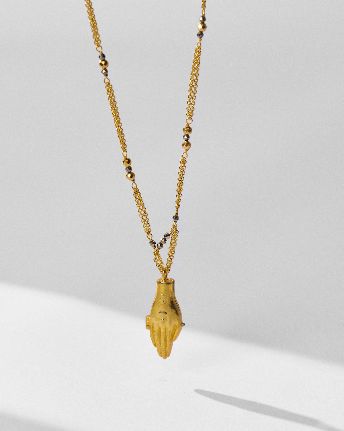 Gold Sama necklace with a hand pendant on a double chain.