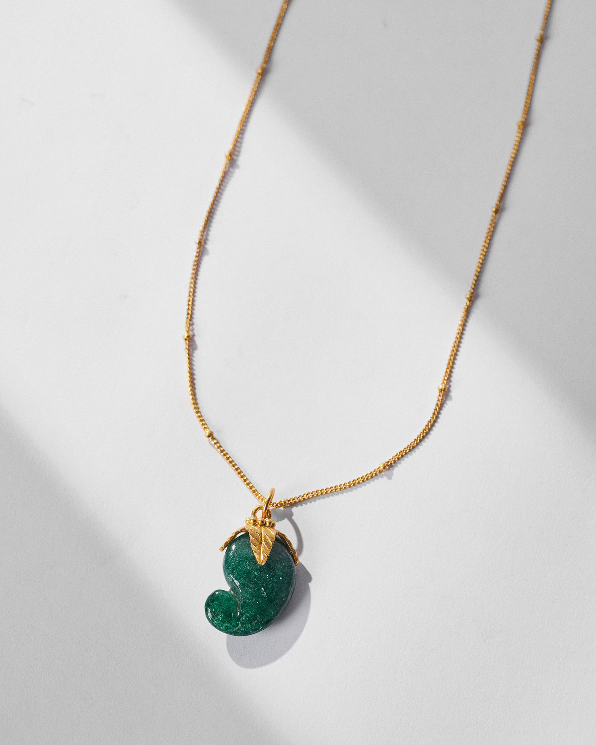 Close-up of the green ambi pendant with a gold leaf cap.