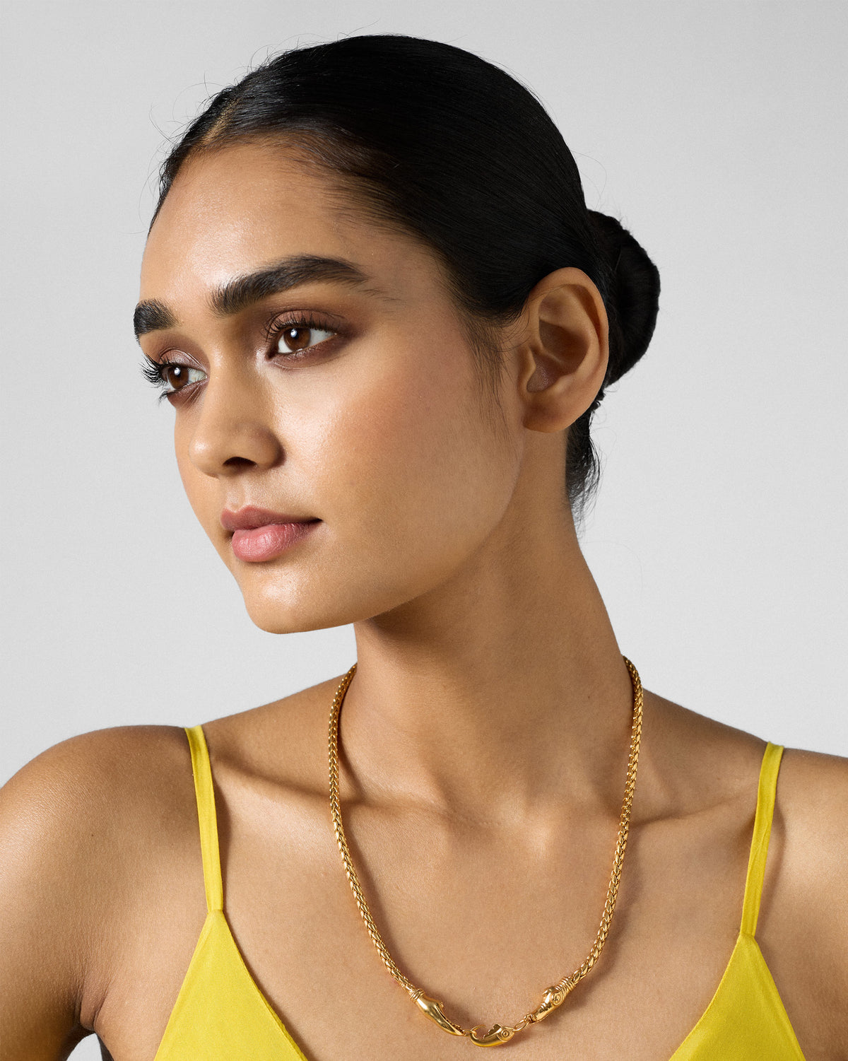 Person wearing a gold Makkar wheat chain with a sculpted front clasp.