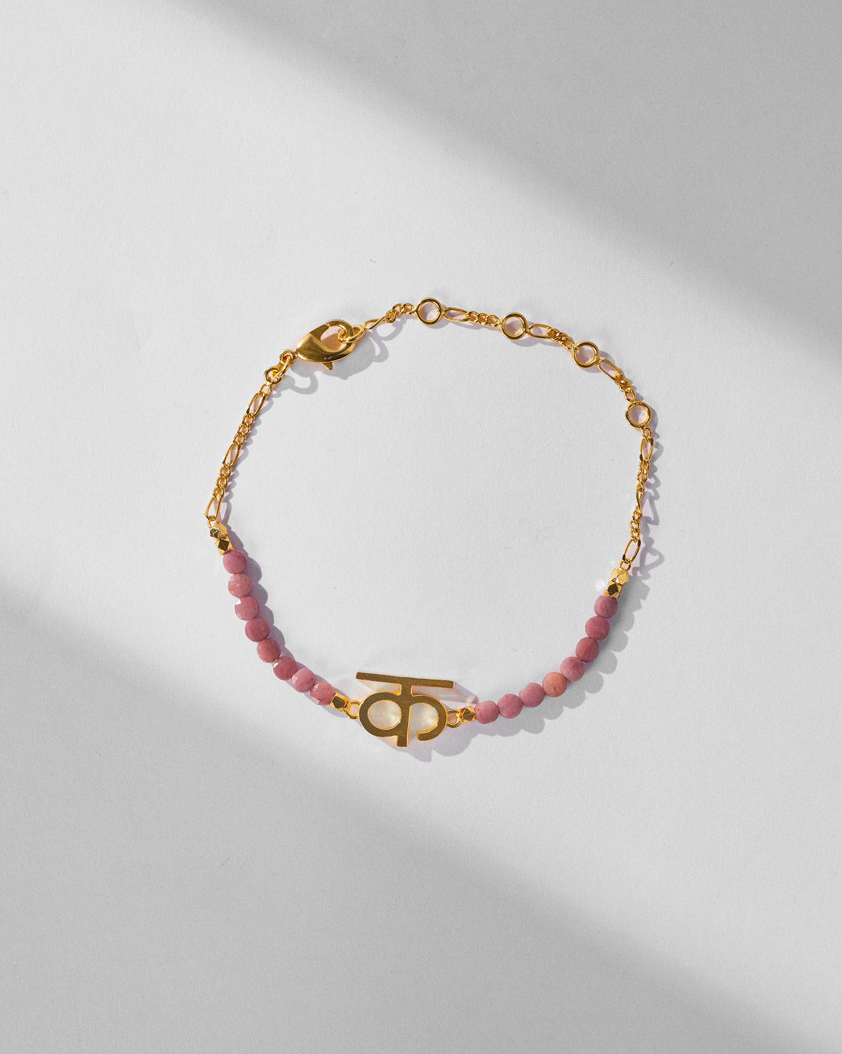Gold Akshar K bracelet looped to show pink beads and extender chain.