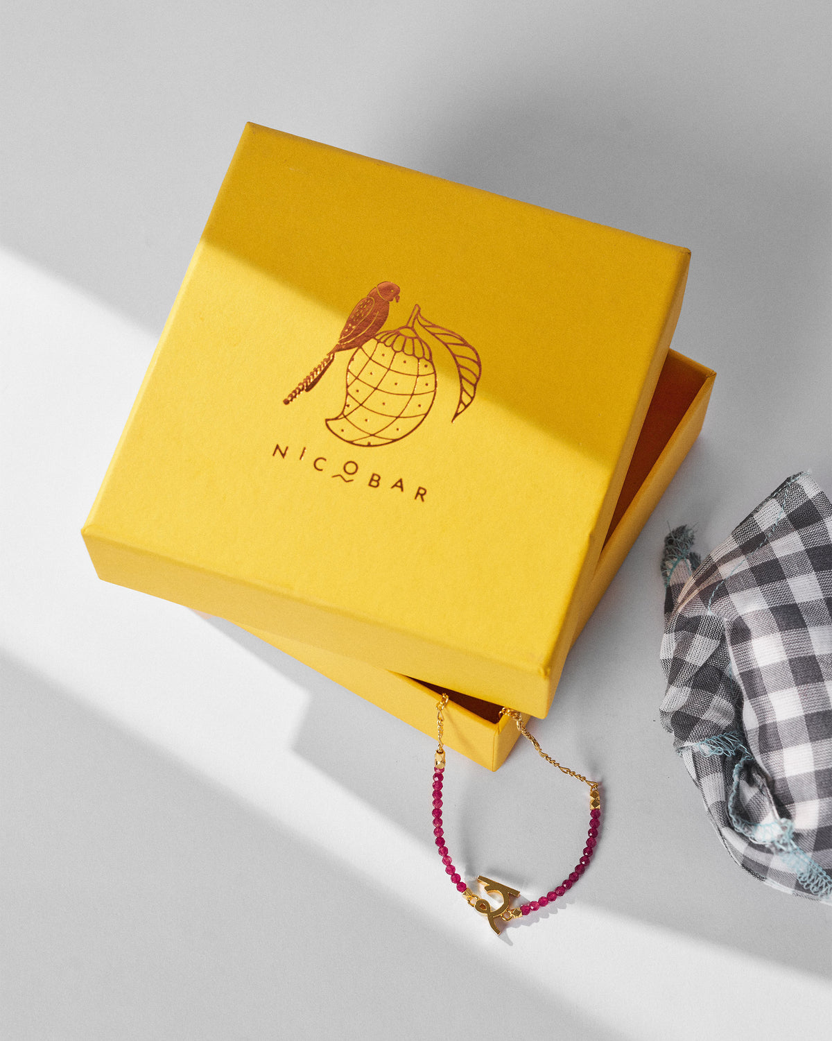 Akshar Bracelet (R) - Gold resting beside a yellow gift box.