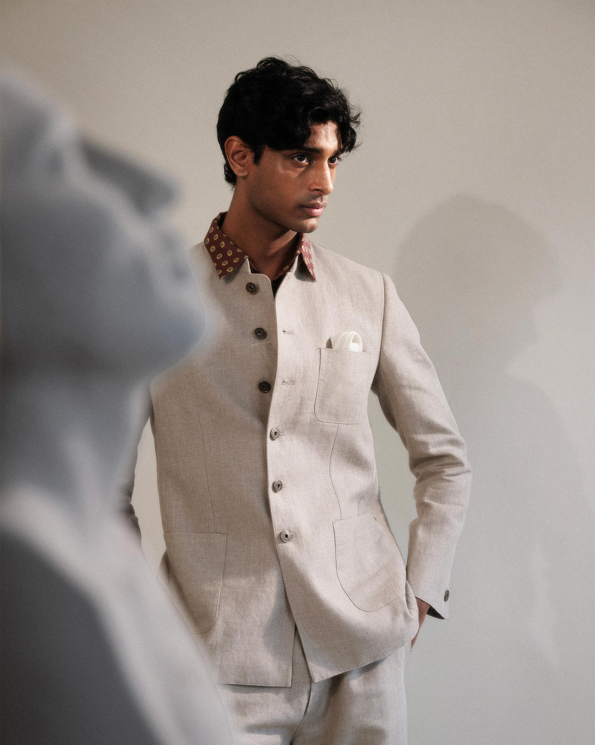 Person wearing a beige linen Tahr bandhgala with patch pockets.
