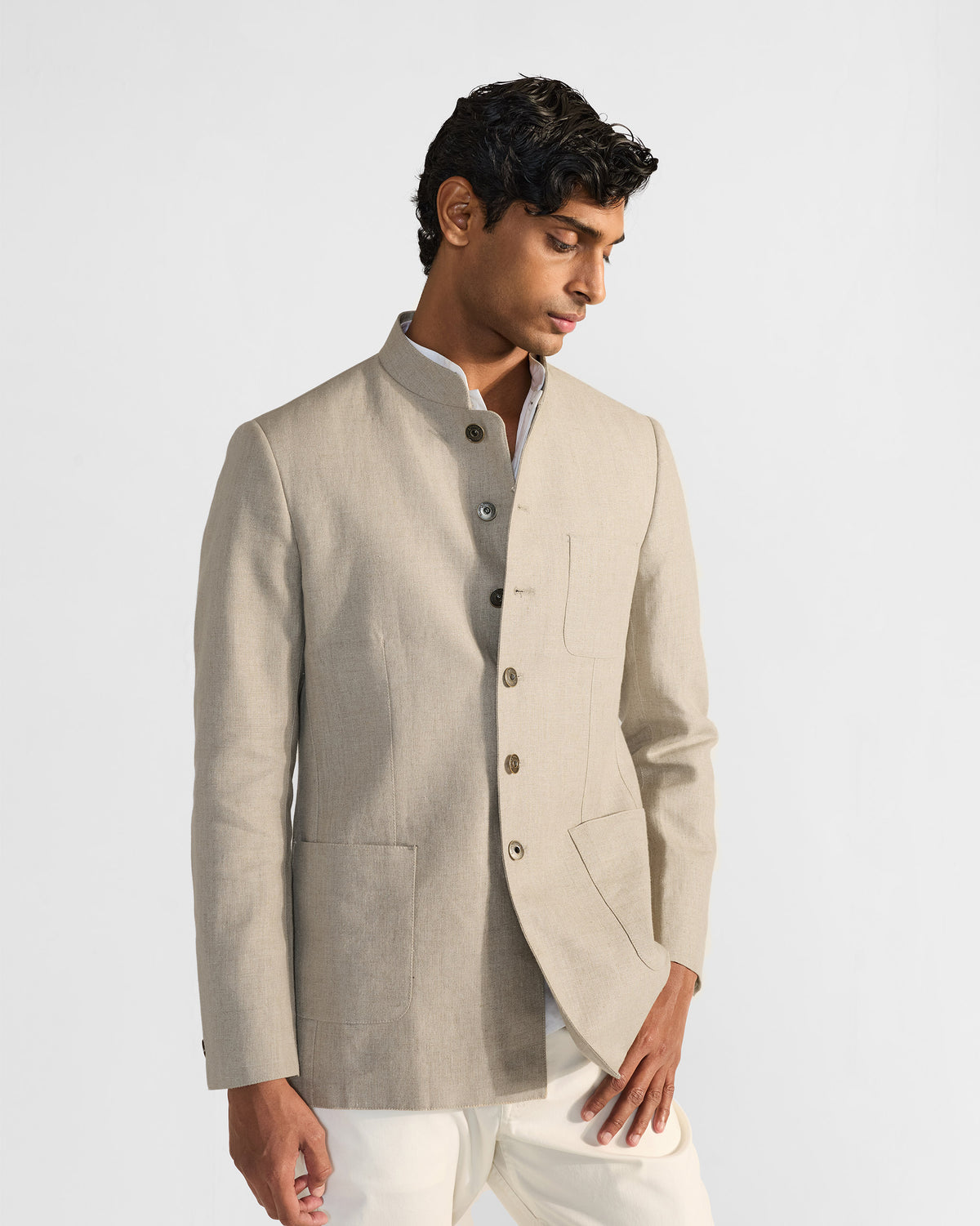 Person wearing a beige linen Tahr bandhgala with three patch pockets.