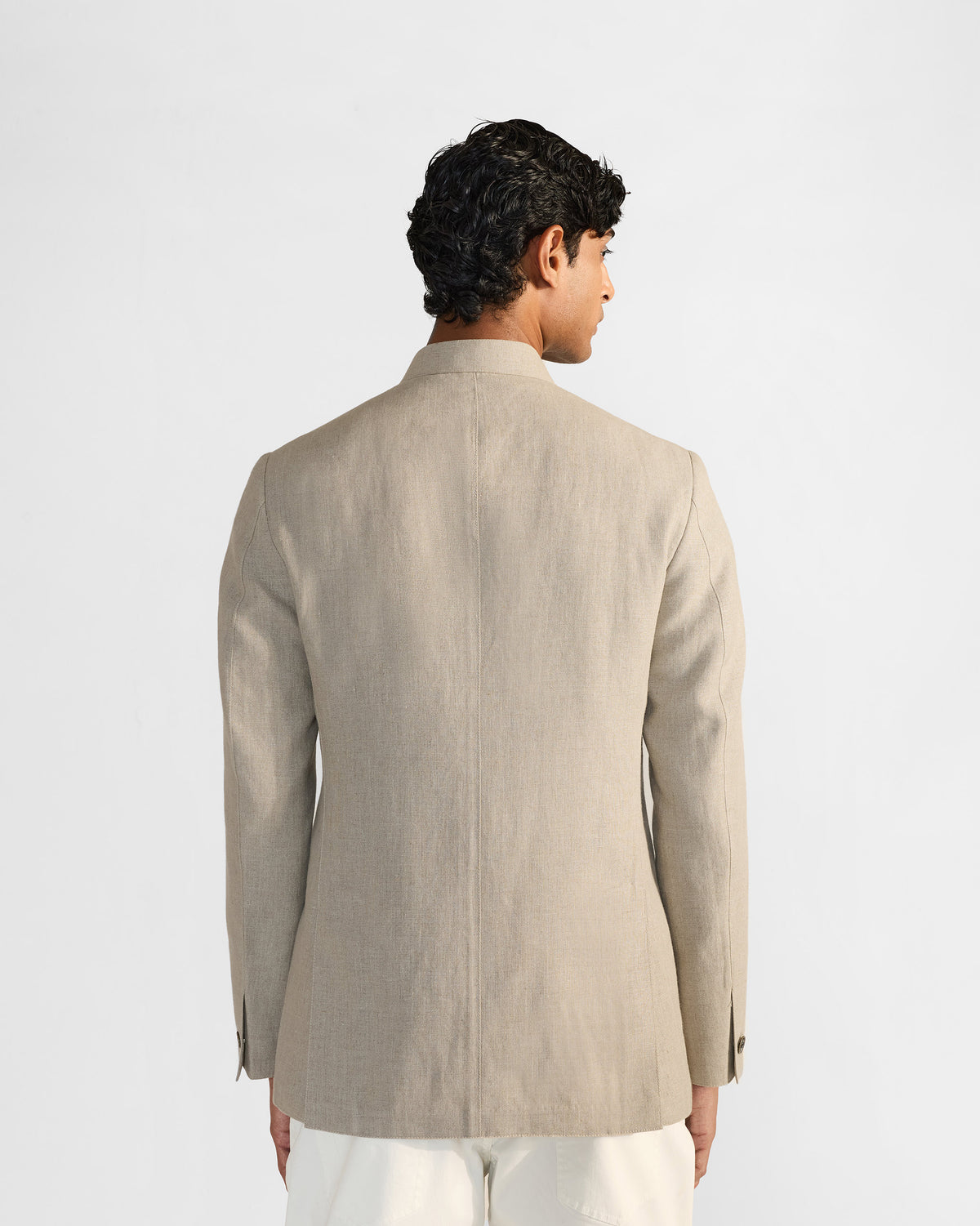 Back of a beige linen Tahr bandhgala with side vents.