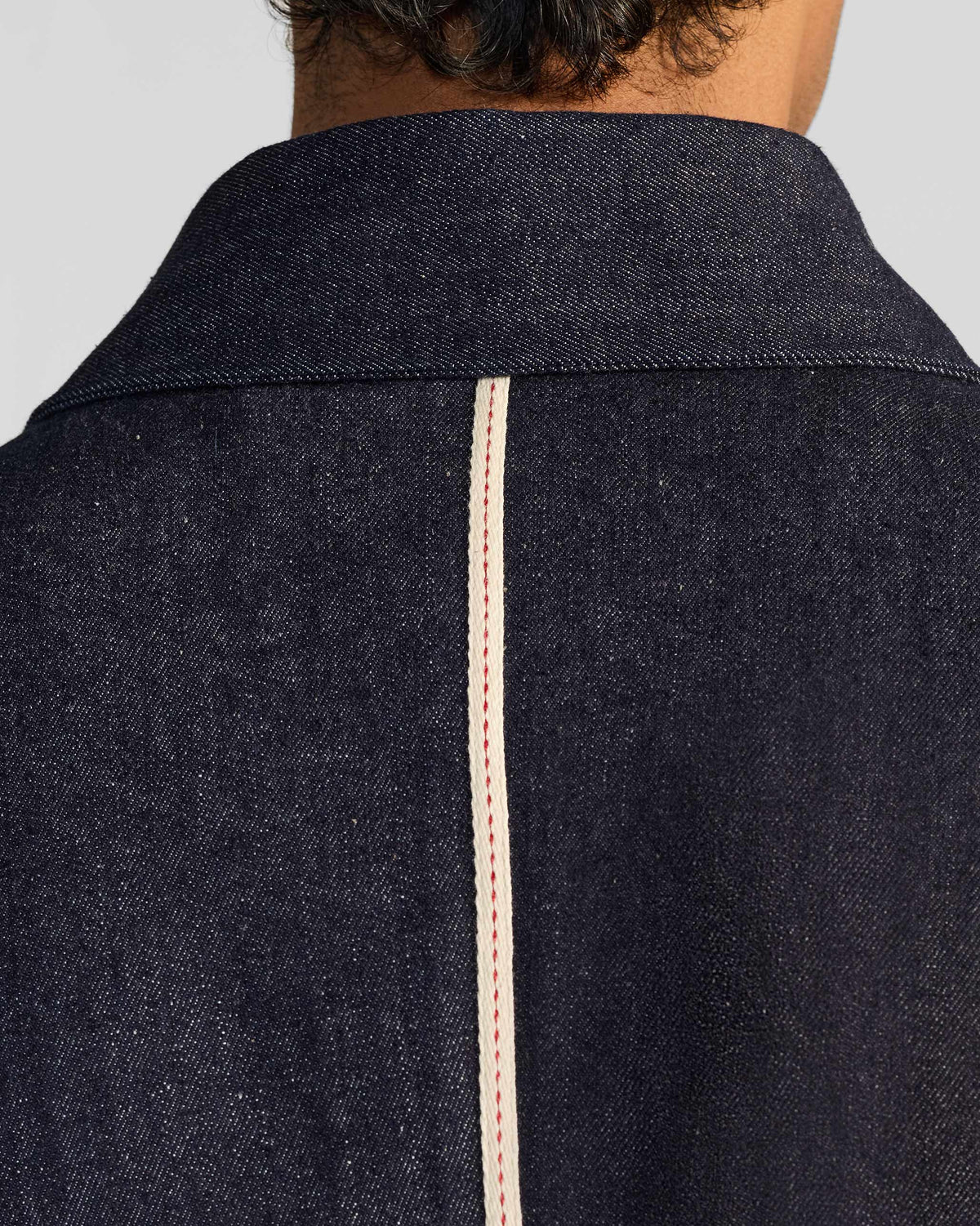 Close-up of the cream back stripe on an indigo denim Ibex travel jacket.