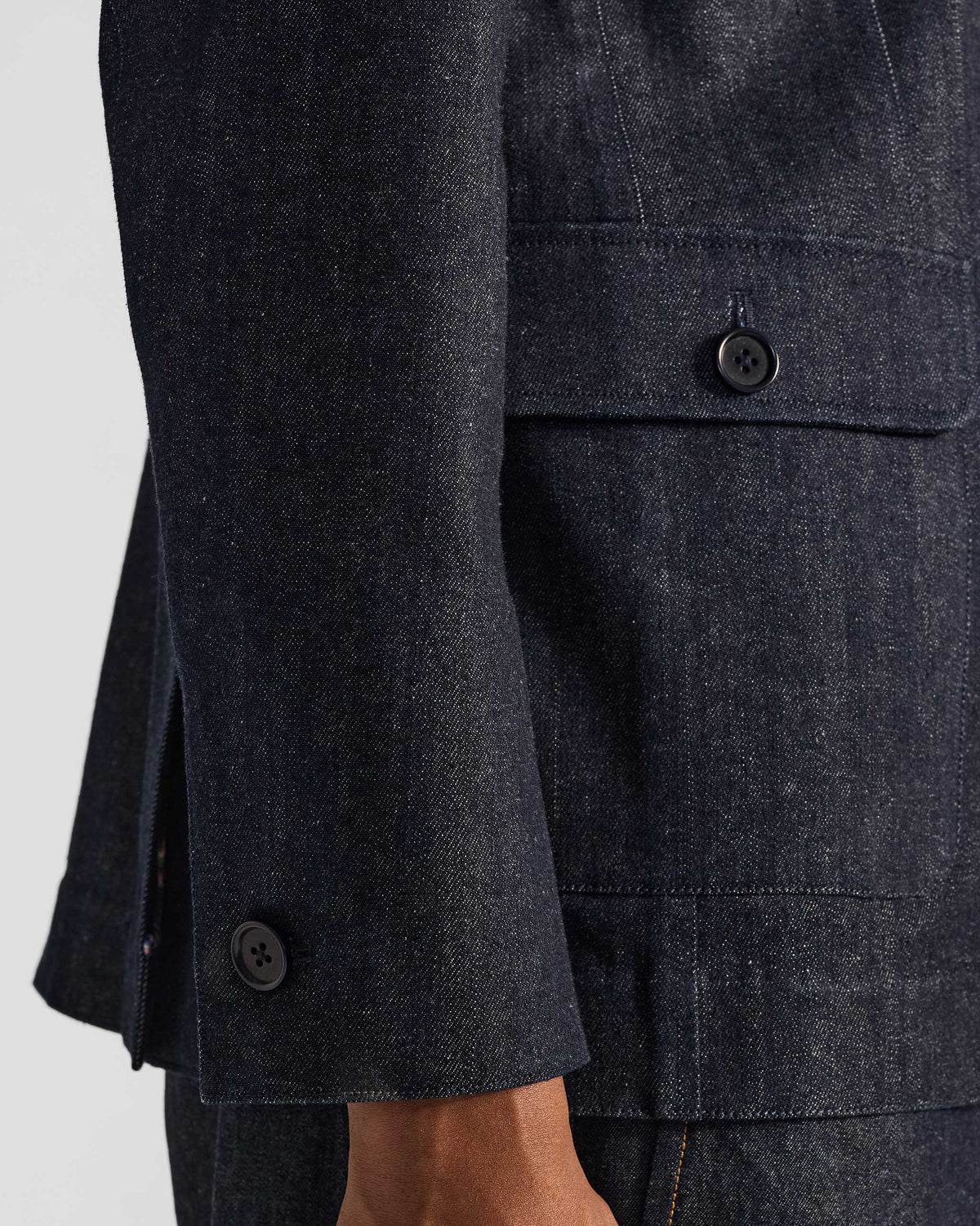Close-up of a flapped pocket and cuff on an indigo denim Ibex travel jacket.