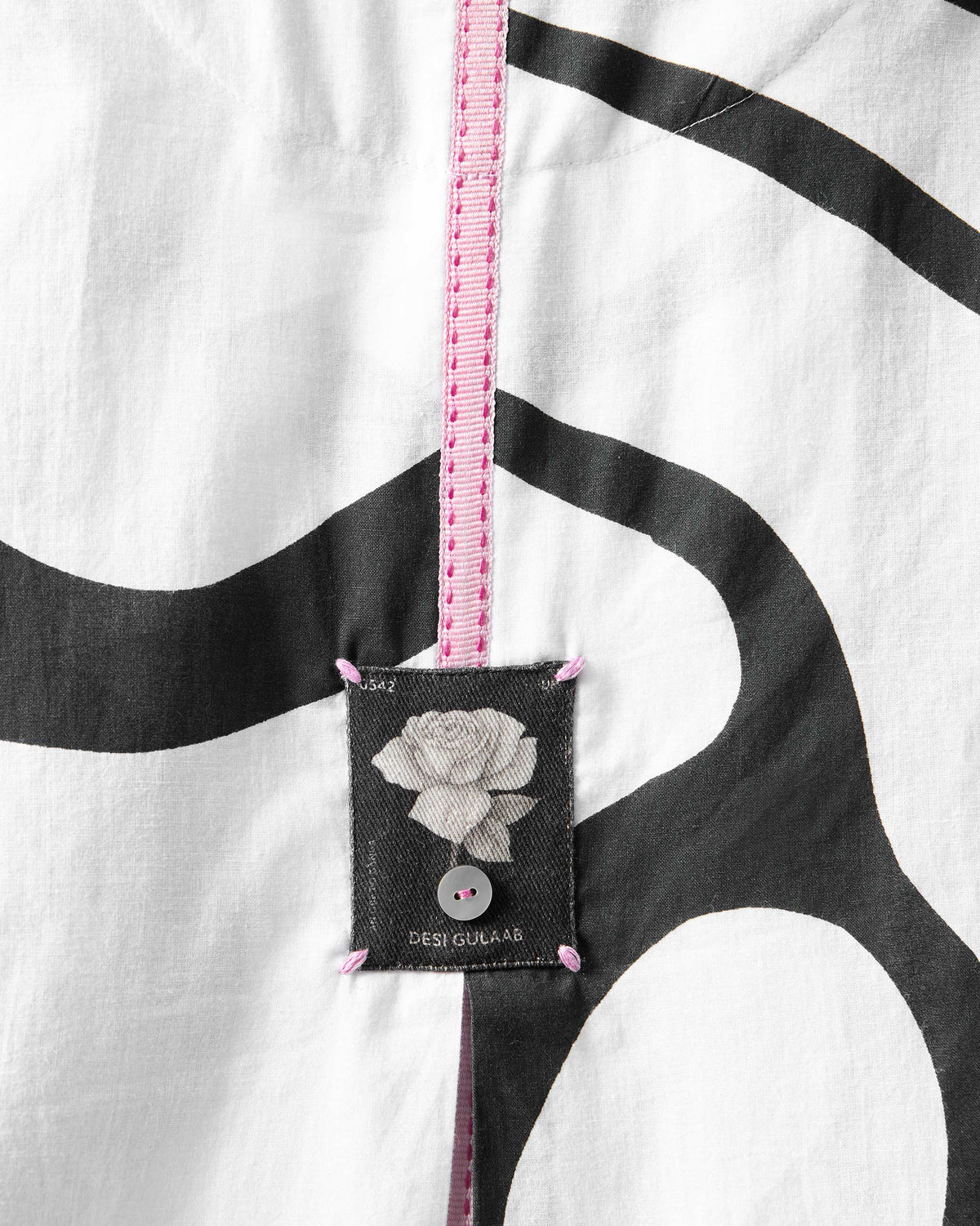 Close-up of an Effy Kaftan back with pink tape and a rose label.