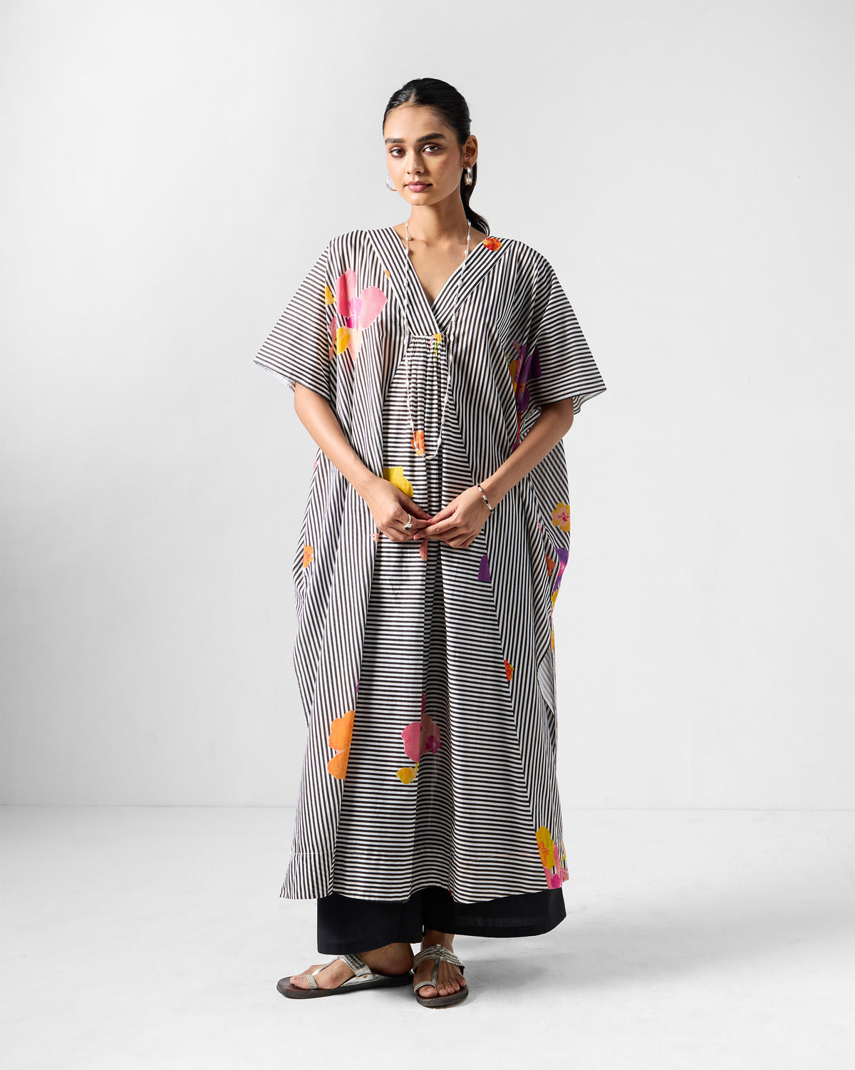 Person wearing a striped Noa kaftan over black trousers.
