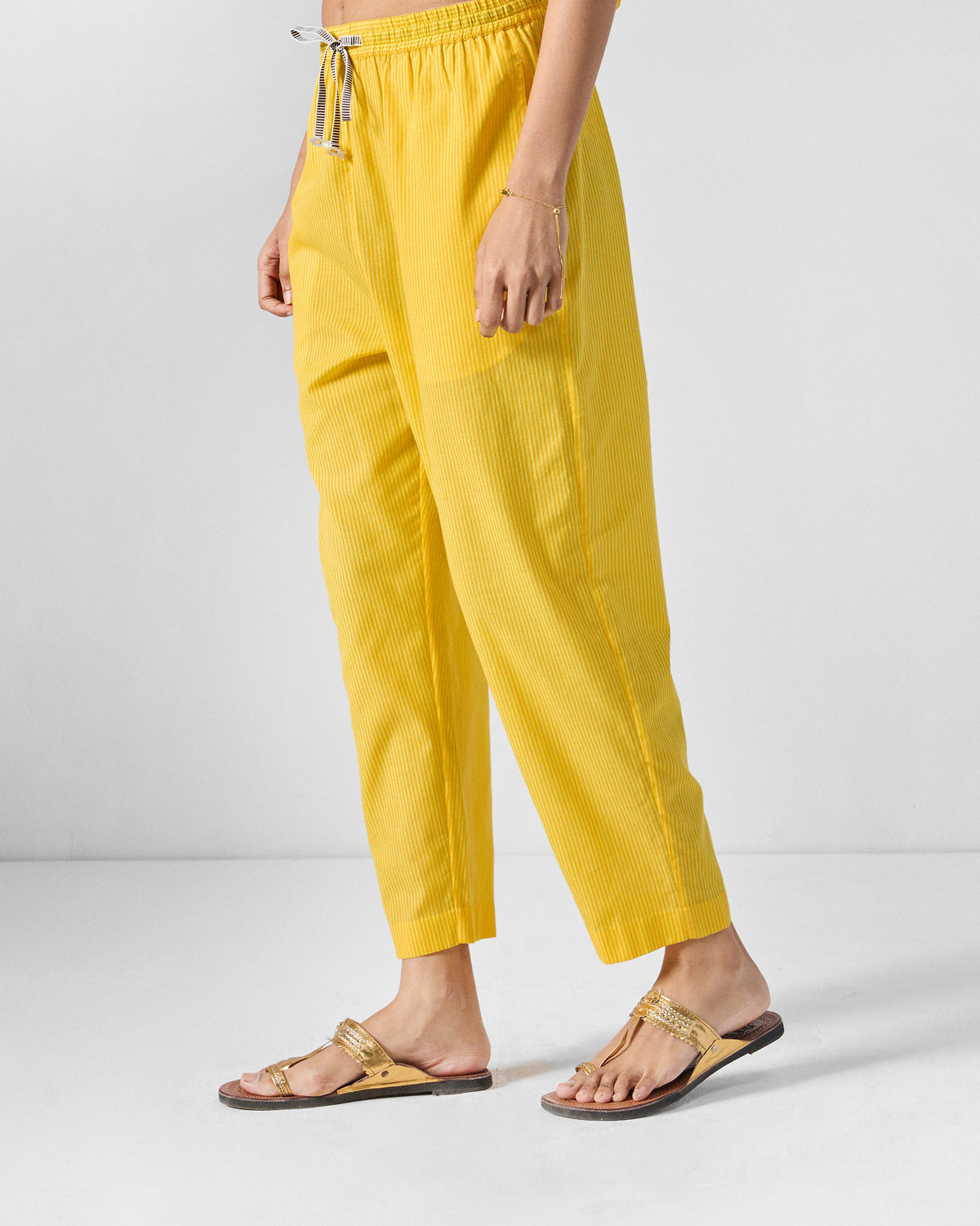Side view of yellow striped Arzoie pants with a tapered cropped hem.
