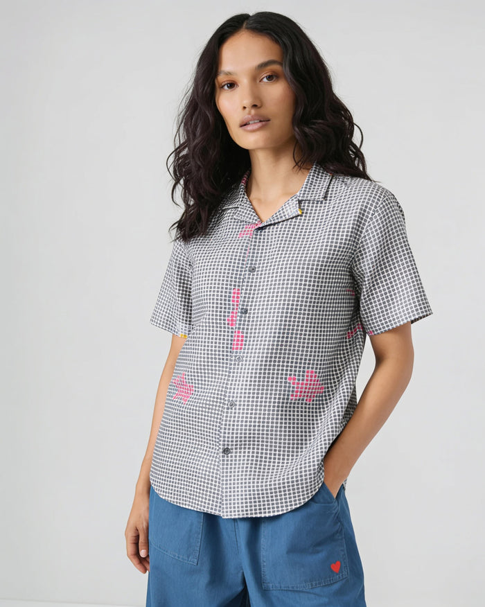 Person wearing a charcoal dot-printed Mistari shirt with pink motifs.