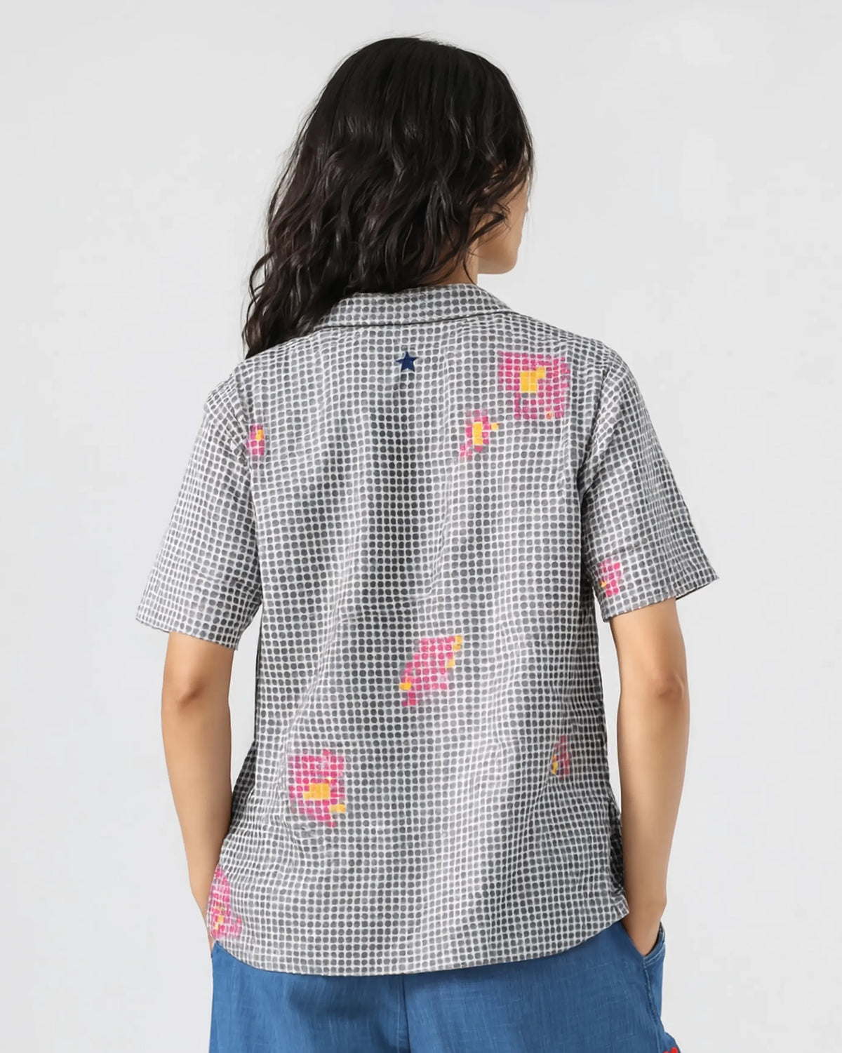 Back of a charcoal Mistari shirt with pink motifs and a navy embroidered star.