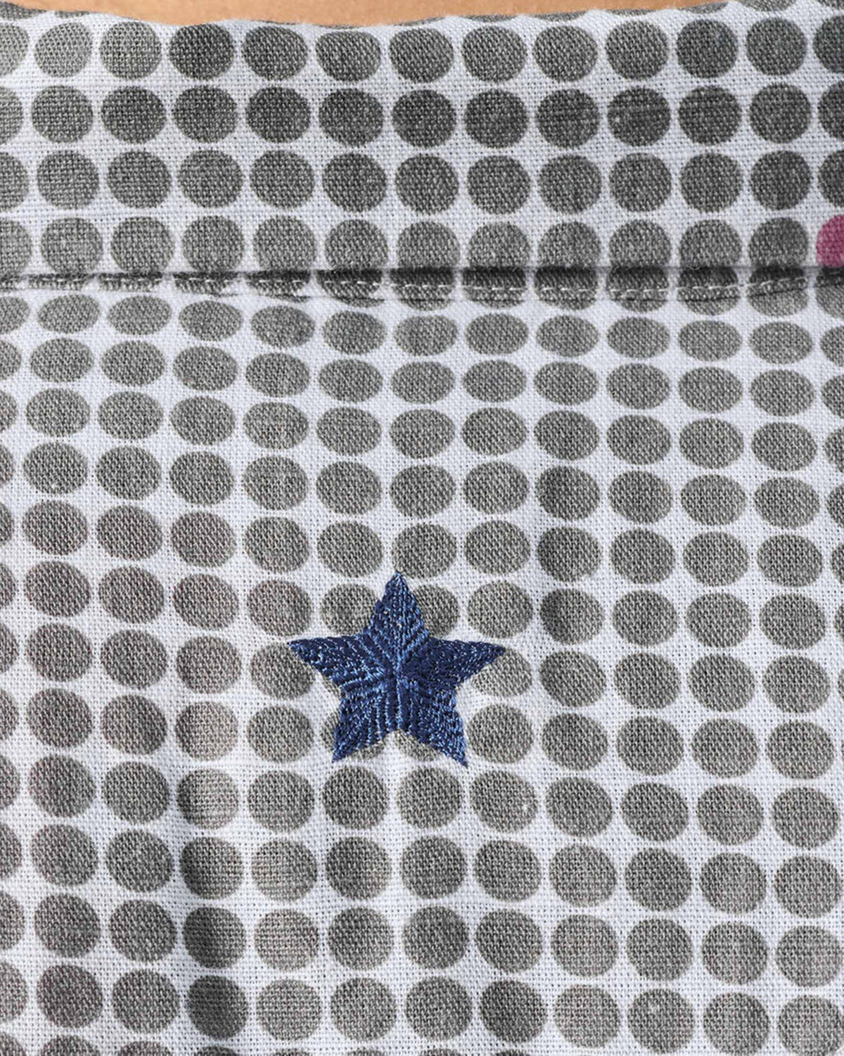 Close-up of a navy embroidered star on charcoal dot-printed Mistari shirt fabric.