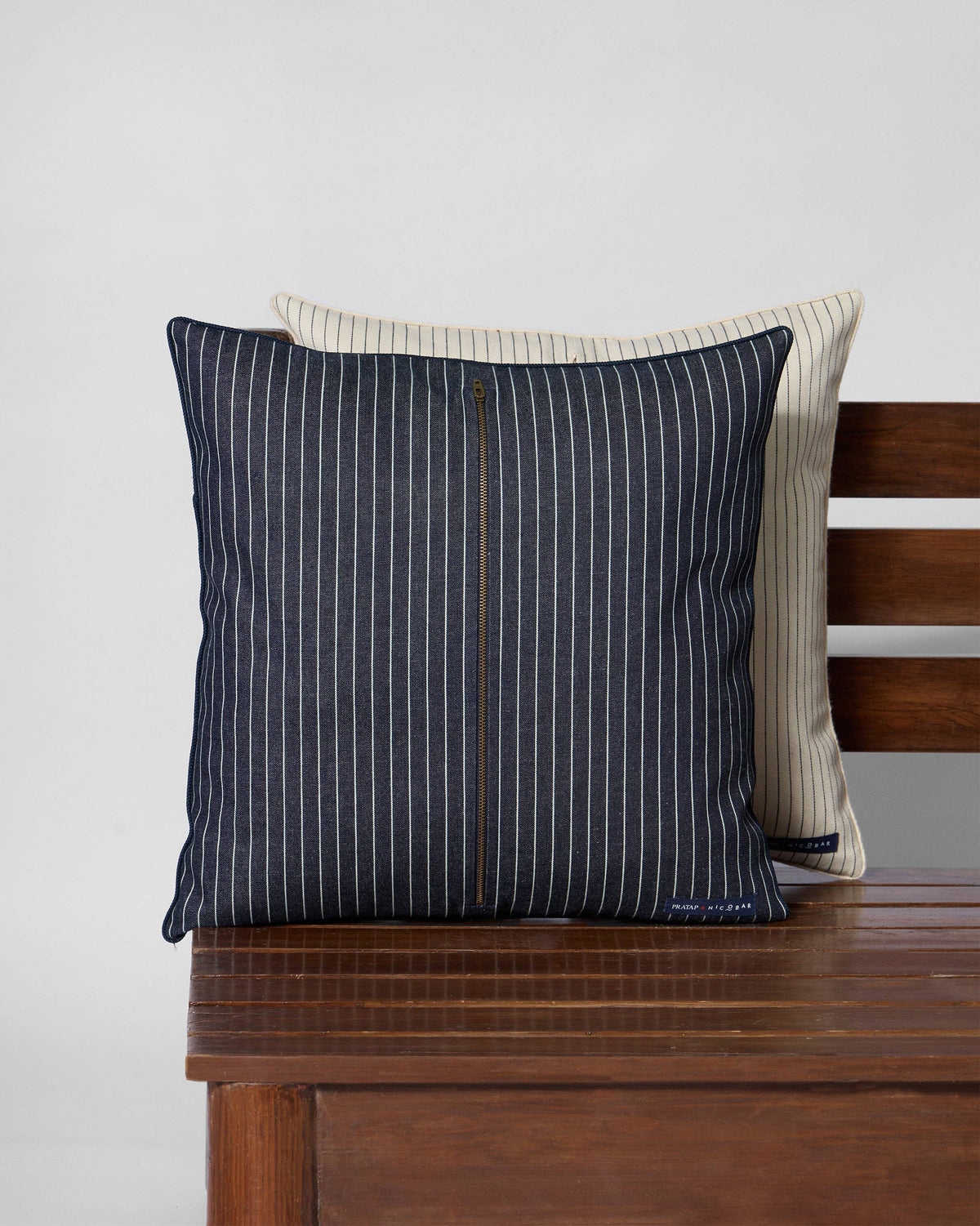 Reverse of a Javandi crewel cushion with navy pinstripes and a central zip.