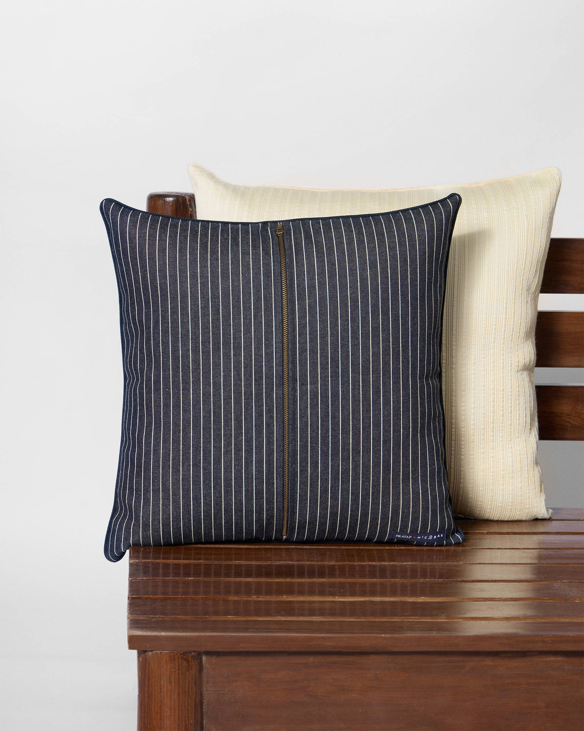 Back of a navy pinstriped Mistflower cushion with a central zip.