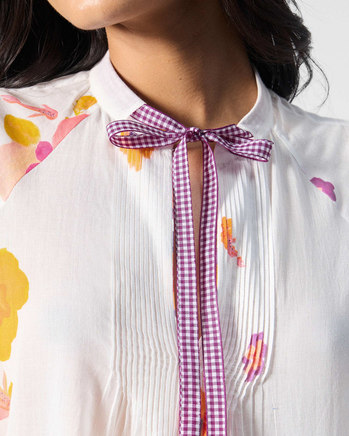 Close-up of Flutter Blouse collar with purple check tie and pintucks.