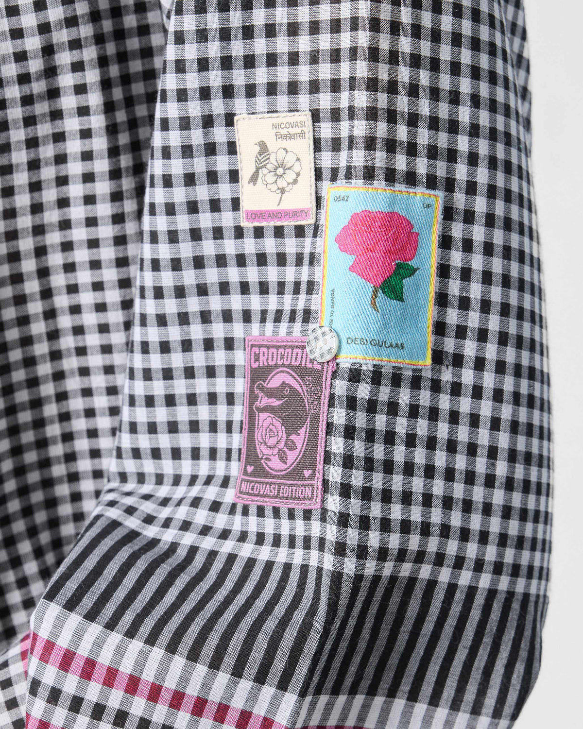 Close-up of black and white checked Leah kurta fabric with embroidered graphic patches.
