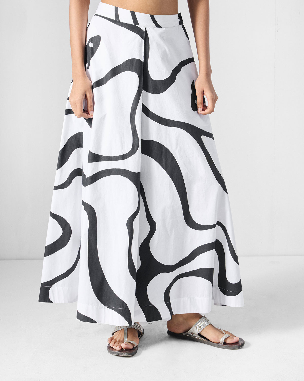Person wearing black and white Ease Flared Pants with a wavy river print.