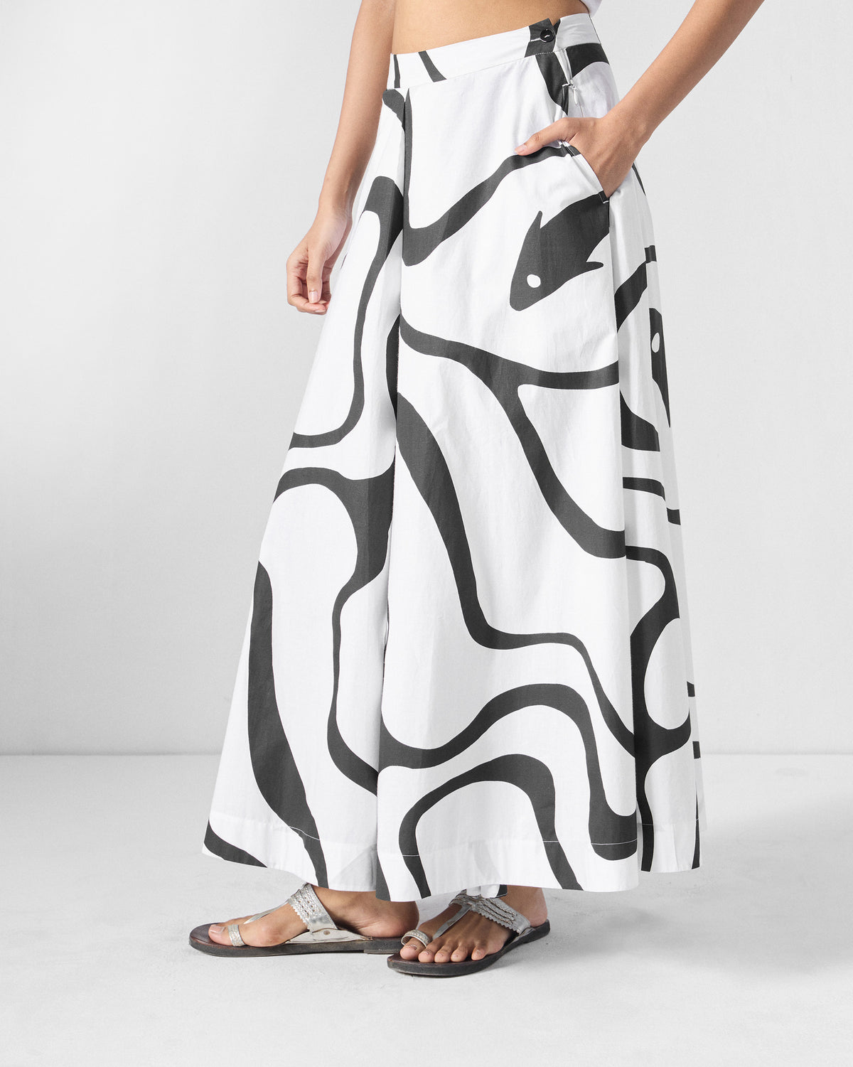 Side view of black and white Ease Flared Pants with a hand in the pocket.