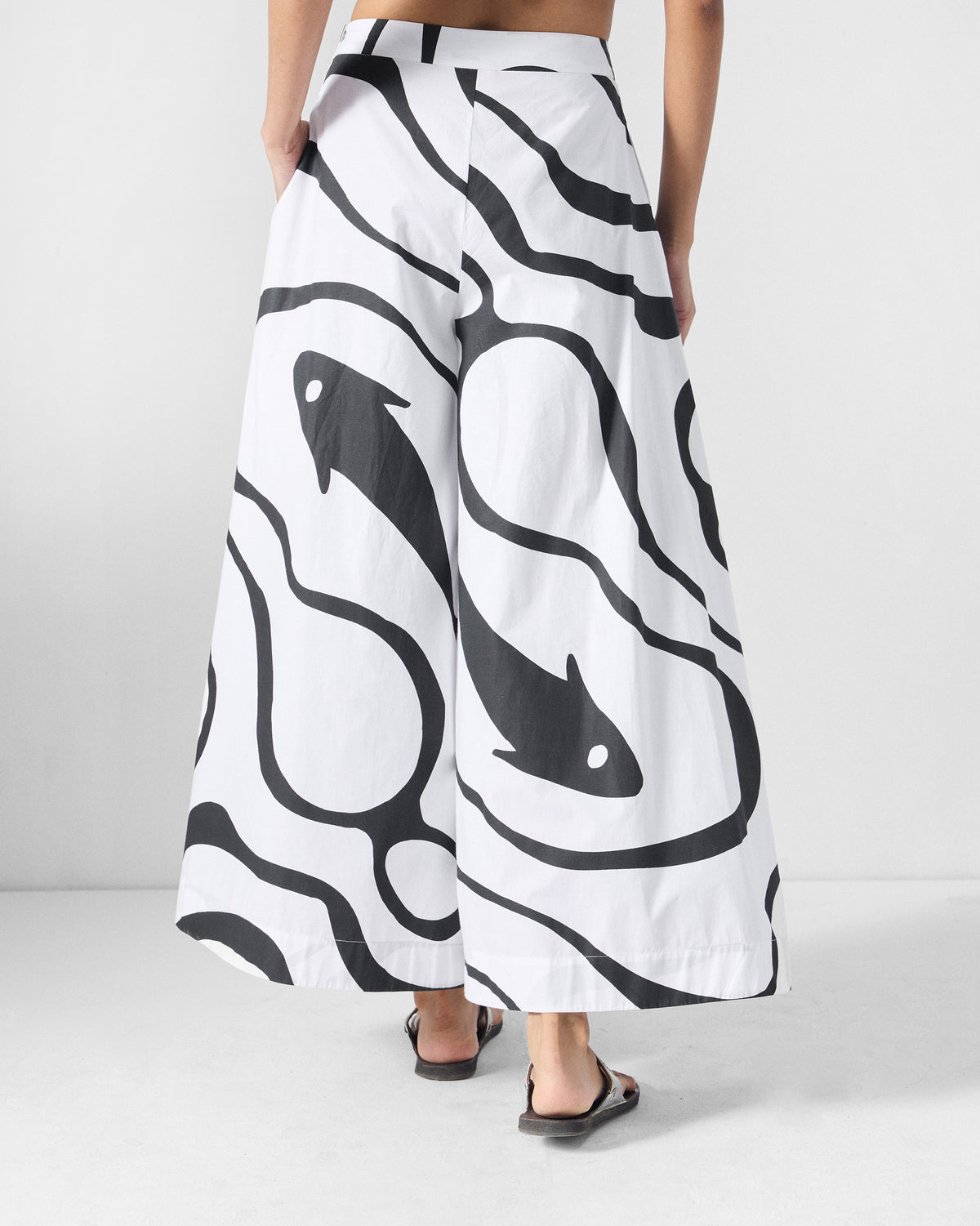 Back of black and white Ease Flared Pants showing fish and river-flow print.