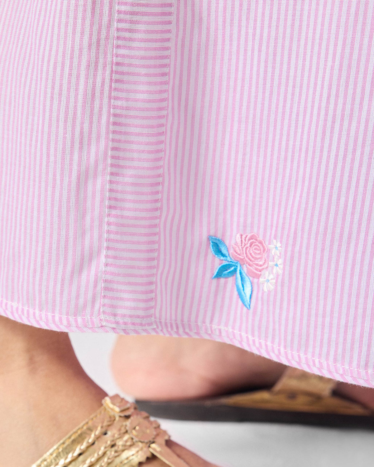 Close-up of a pink rose embroidery on pink and white striped Ceylon pants.