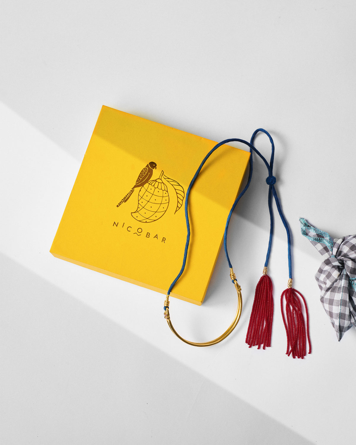 Gold baju bandh beside a yellow Nicobar gift box.