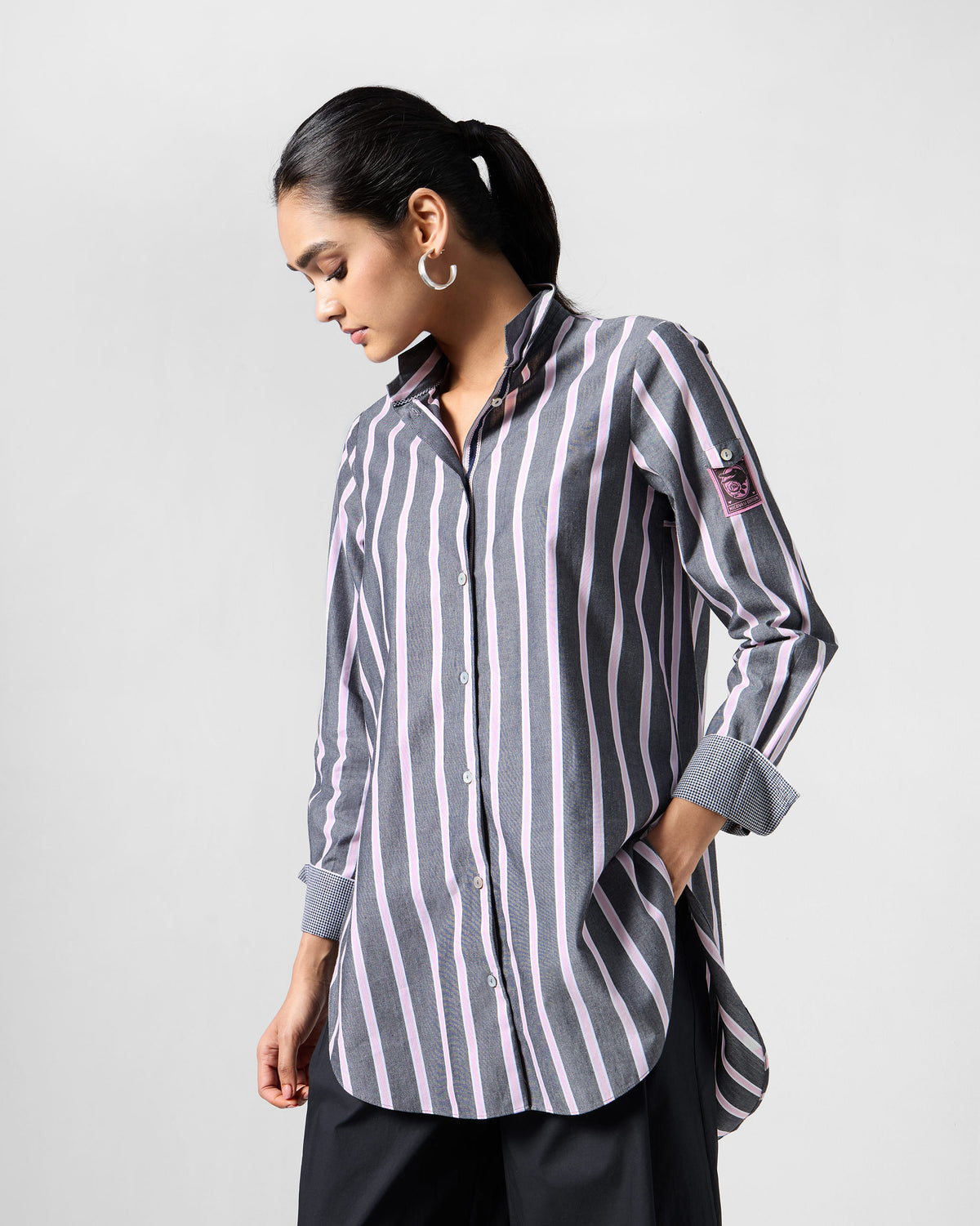 Person wearing a charcoal and pink striped Trench shirt with a pink sleeve patch.