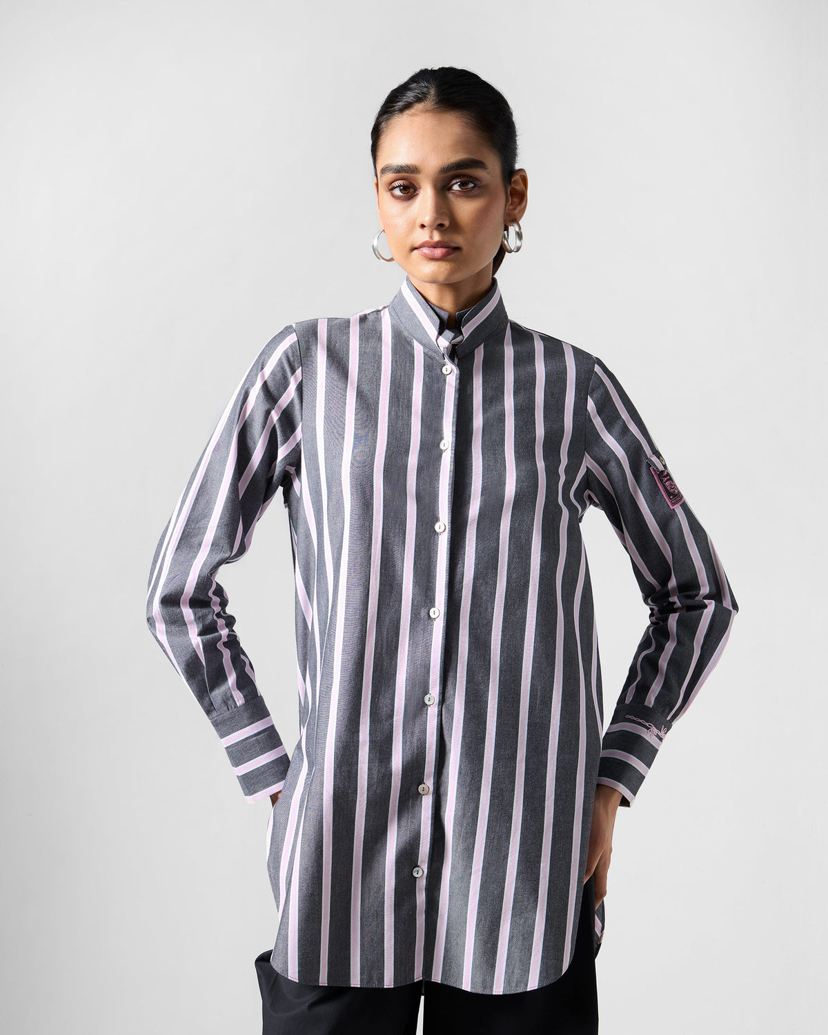 Person wearing a charcoal and pink striped Trench shirt with a stand collar.