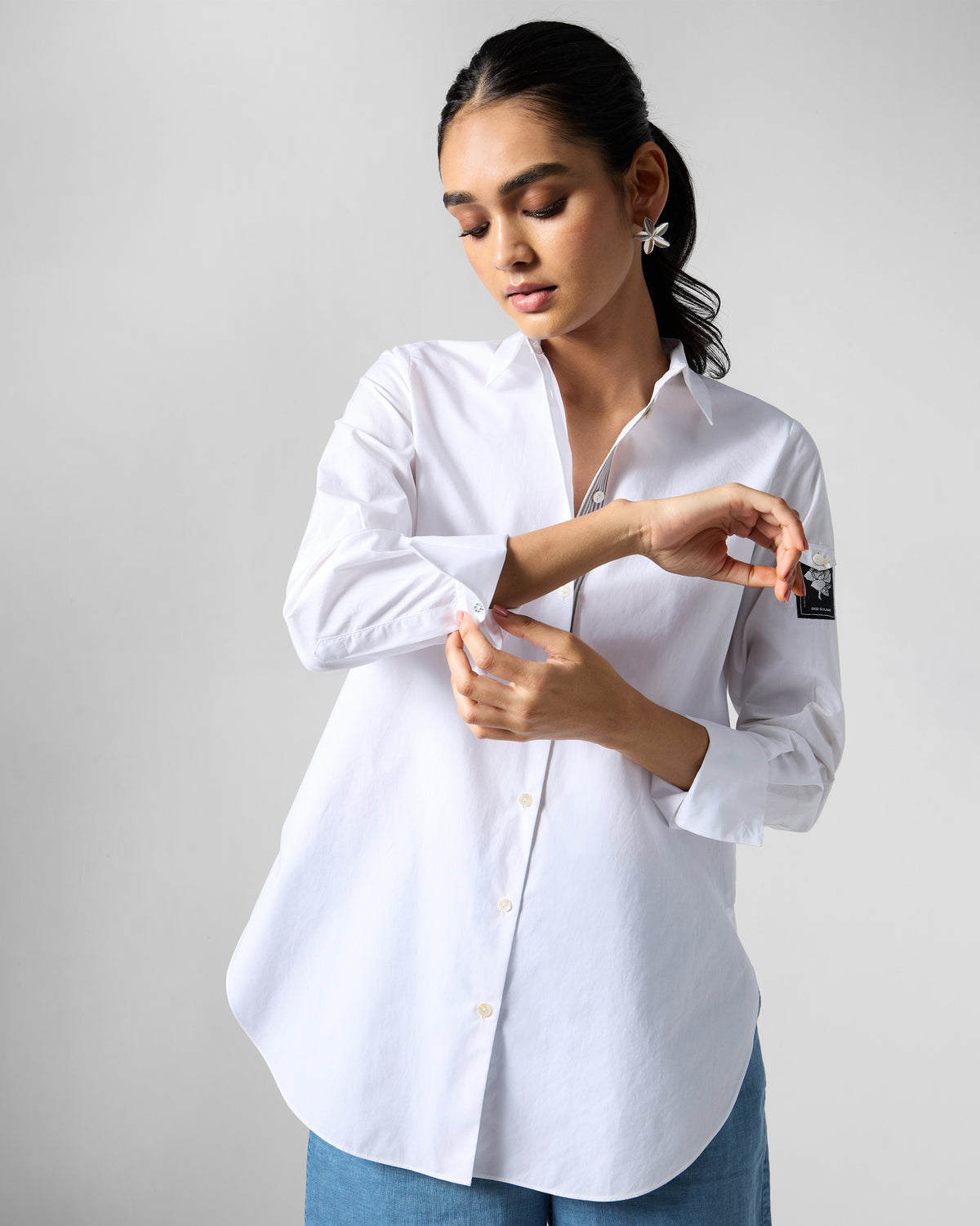 Person wearing a white Trench shirt while adjusting the cuff.