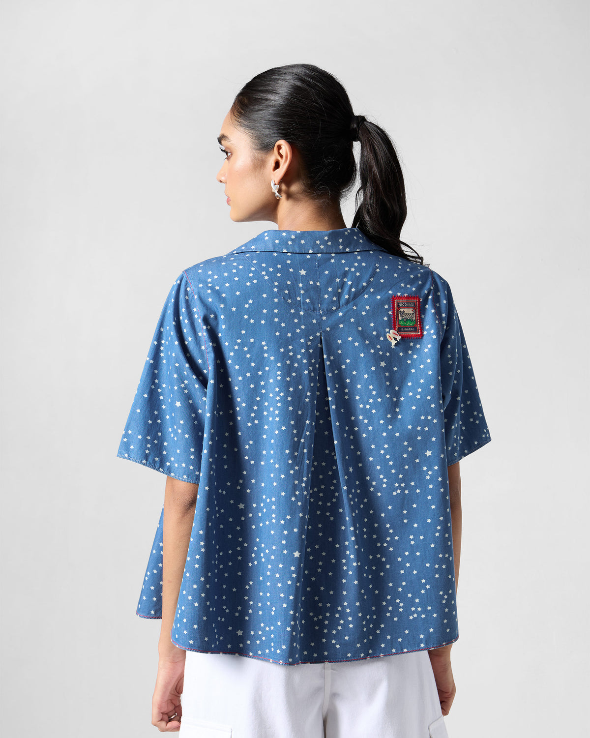 Back of a blue Swing top with a white star print and box pleat.