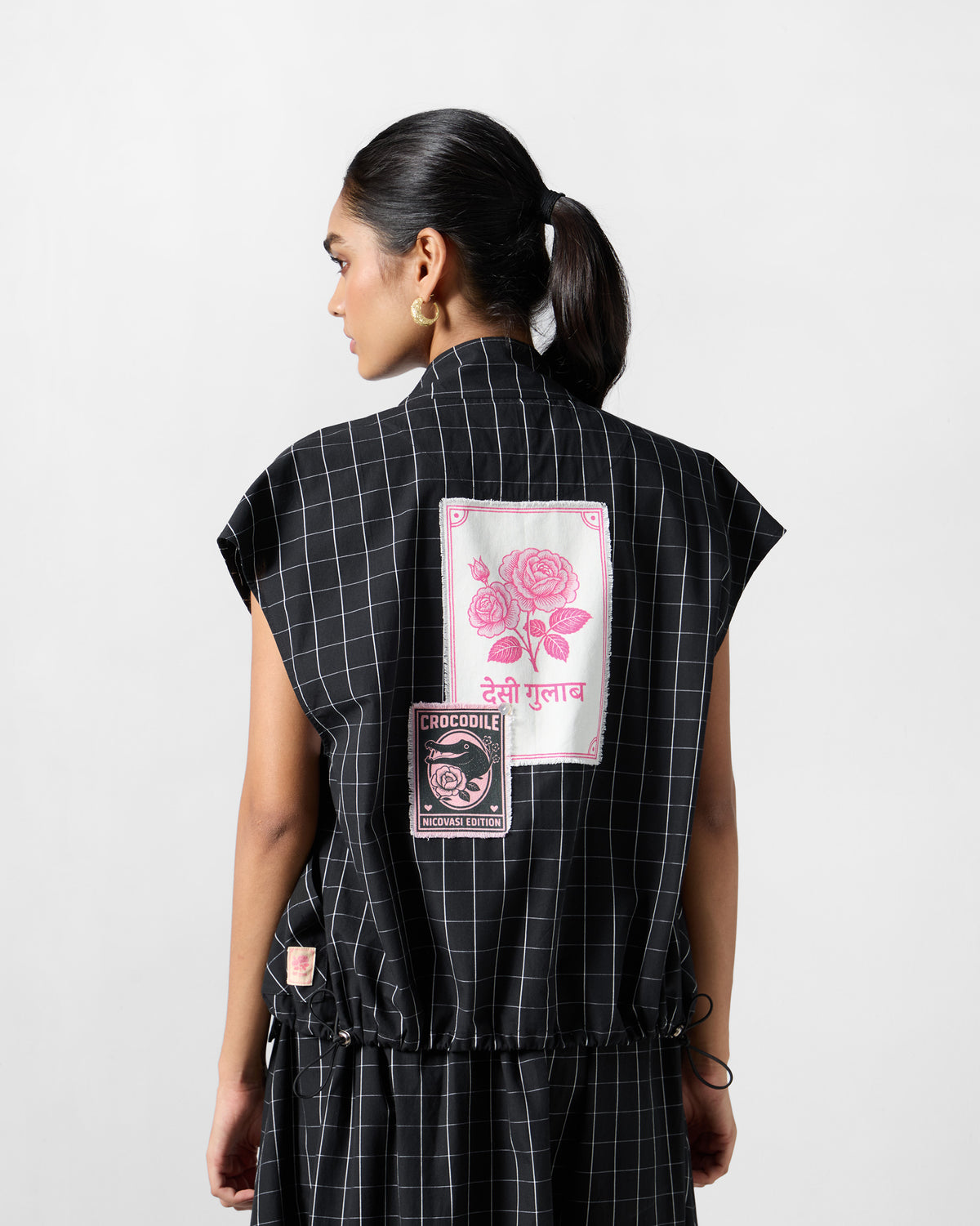 Back of a black-and-white checked Renai top with rose and crocodile patches.