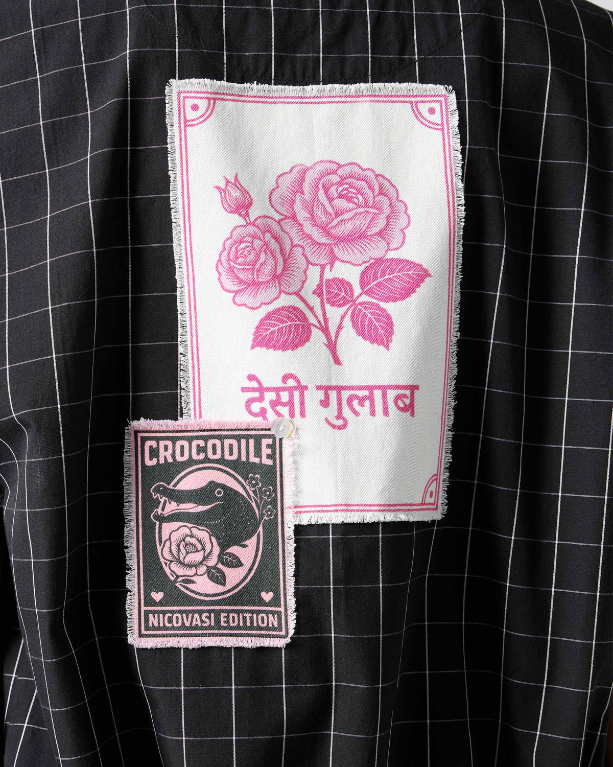 Close-up of rose and crocodile patches on a black-and-white checked Renai top.