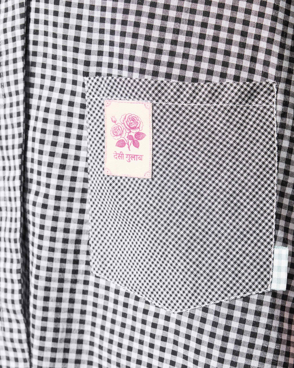 Close-up of a black and white check shirt pocket with a pink rose stamp.