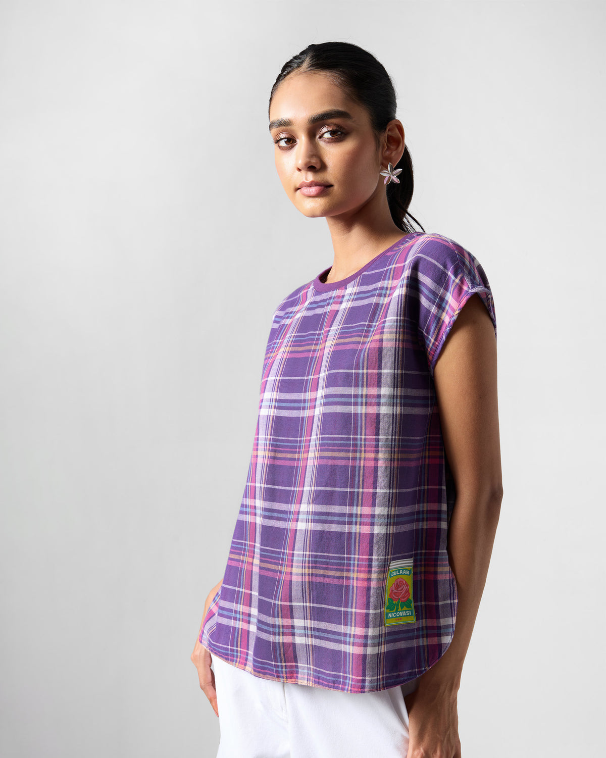 Person wearing a purple plaid Flow top with a green rose patch.