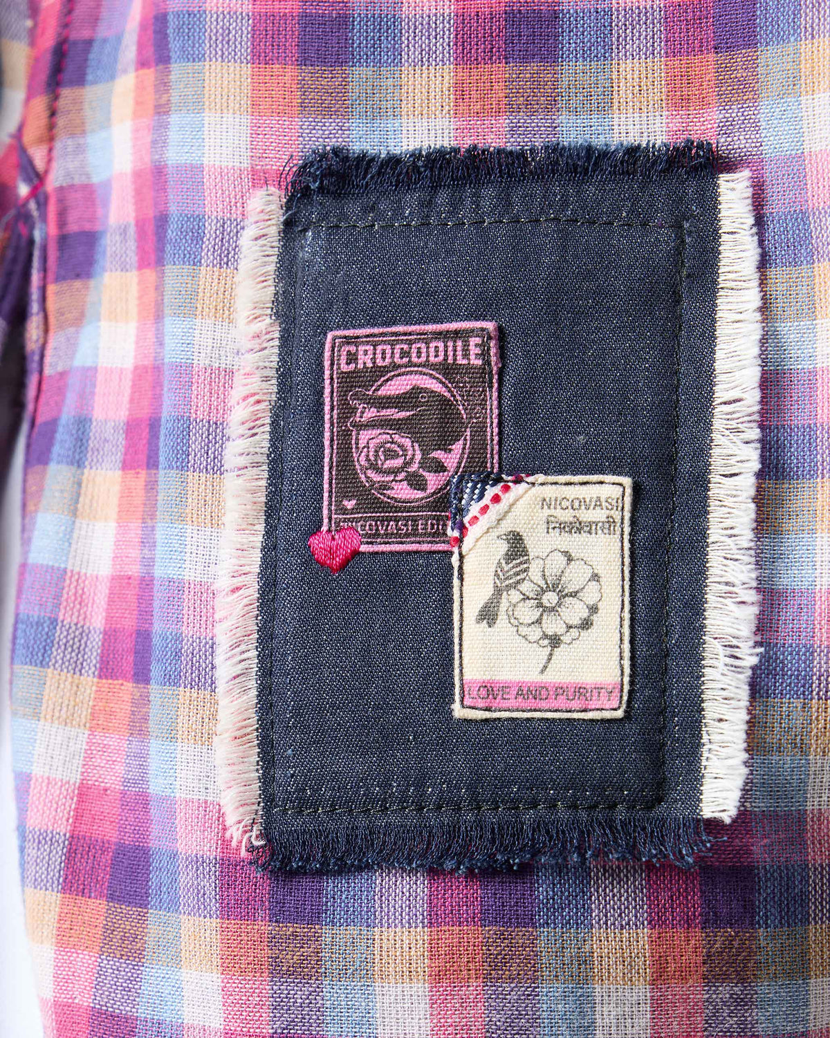 Close-up of the denim brand patch on a purple check Flow top.