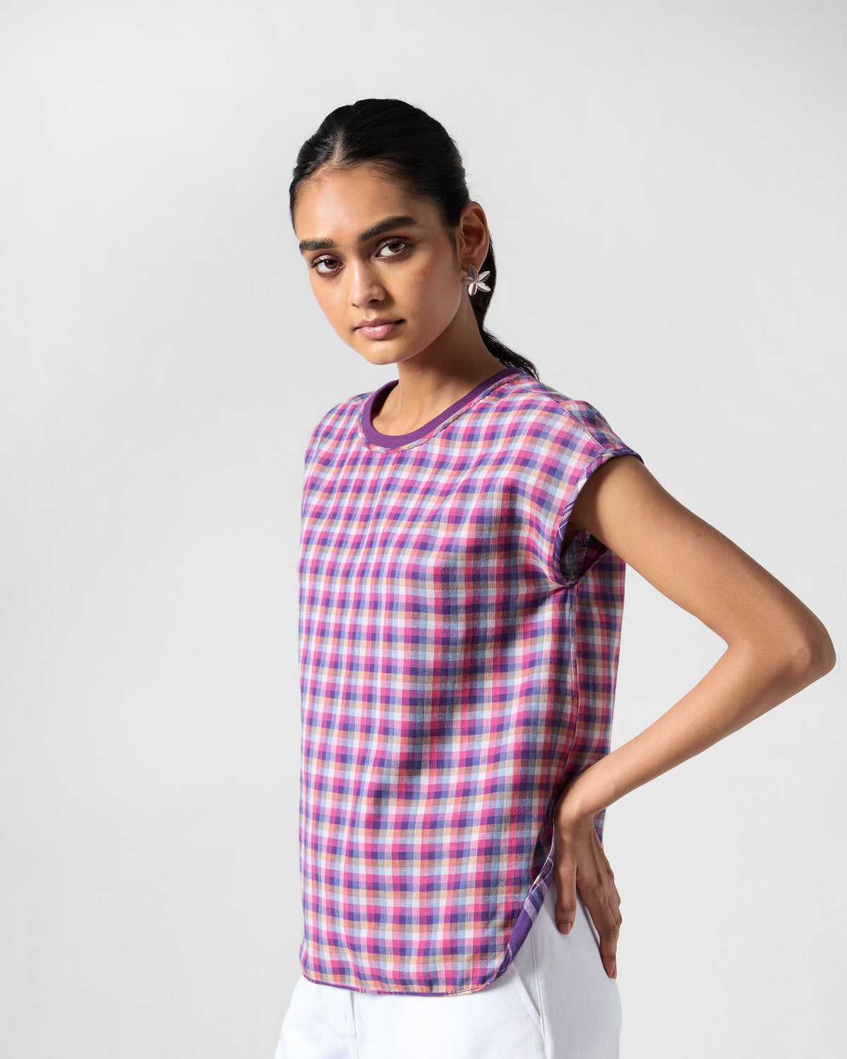 Person wearing a sleeveless purple check Flow top with purple trim.