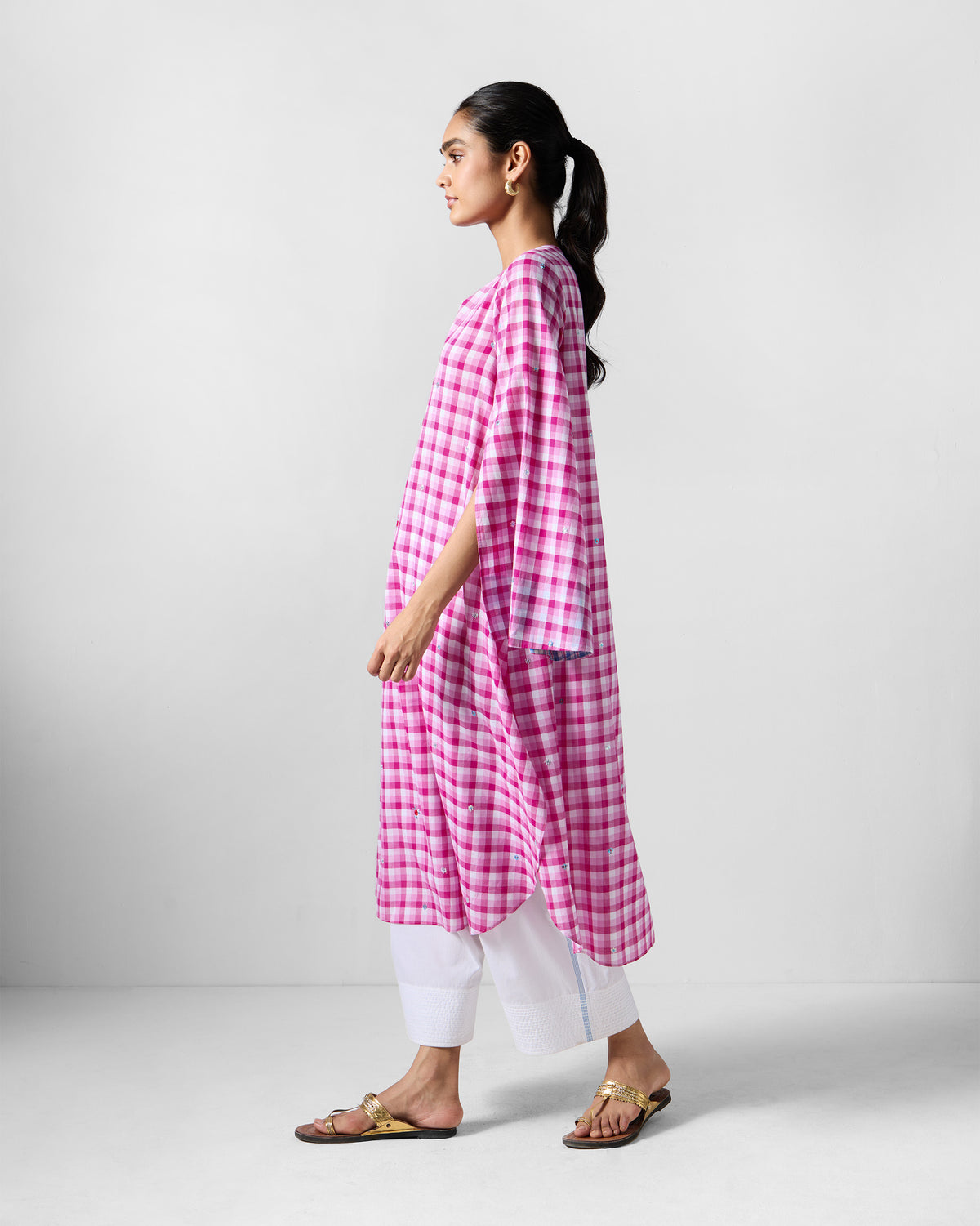 Side view of a pink and white check embroidered Amaya tunic worn by a person.