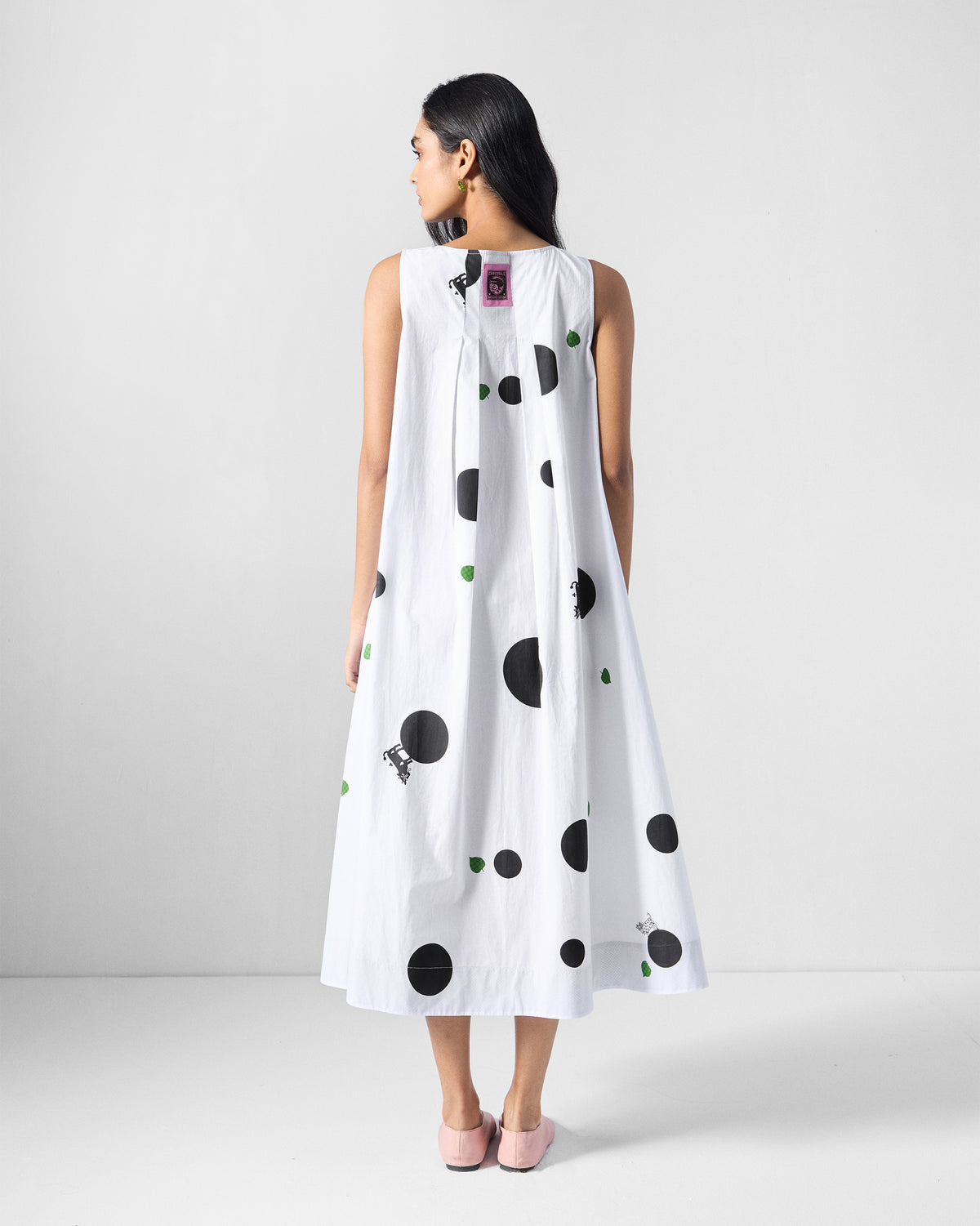 Back of a white polka-dot midi dress with a pink neck label.