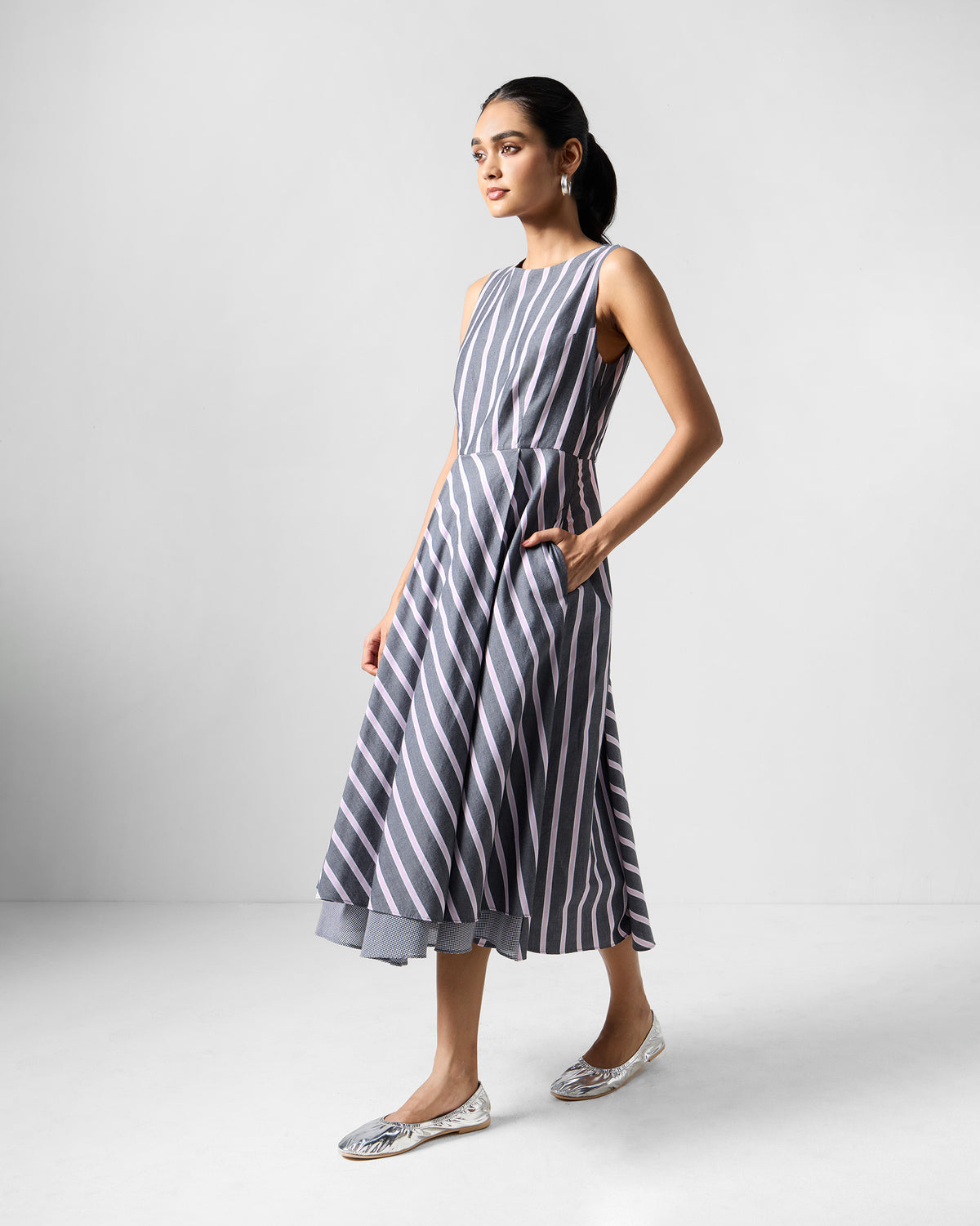 Person wearing a charcoal and pink striped Tapas layered dress with a side pocket.