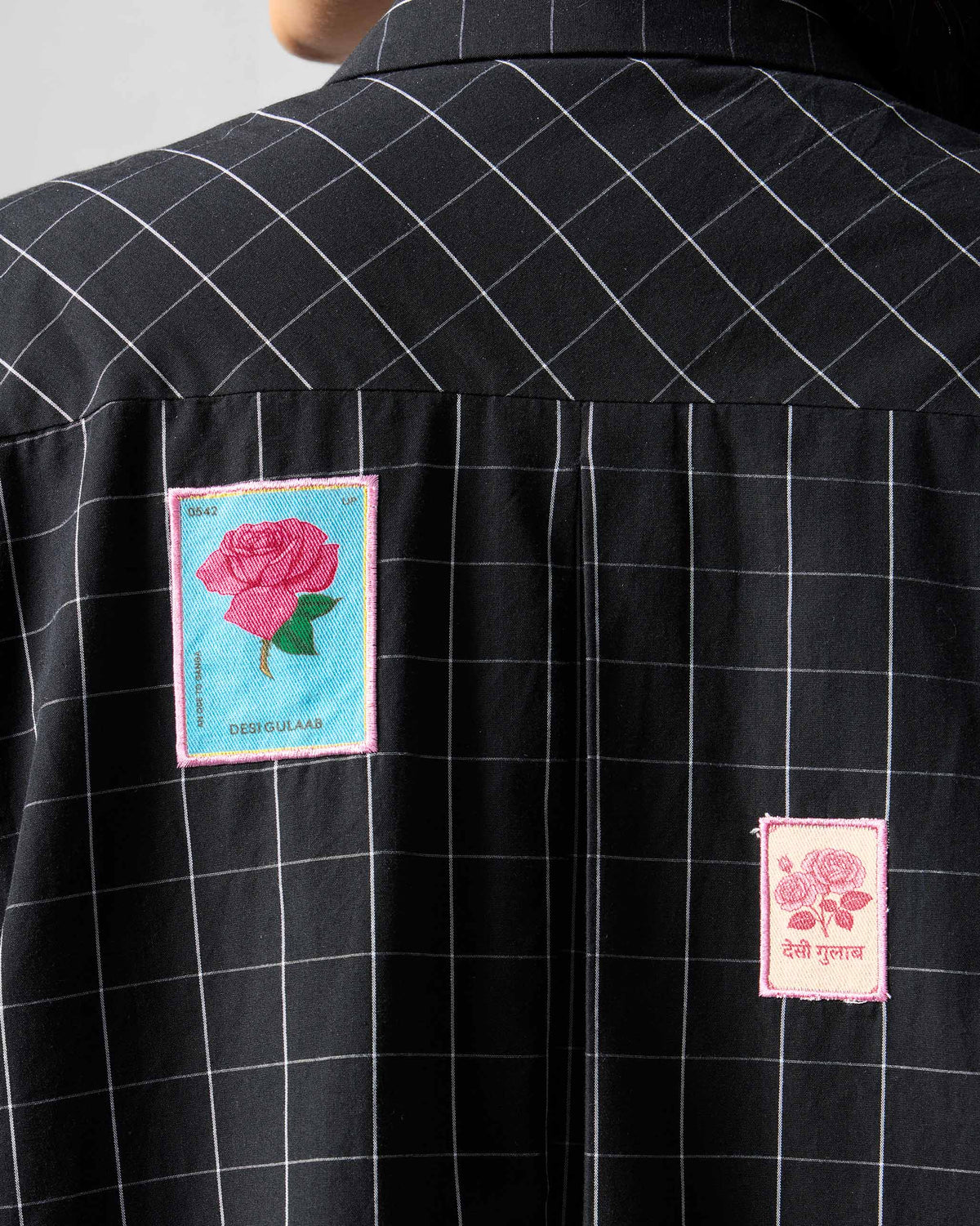 Close-up of rose patches on the back of a black check Spiti dress.