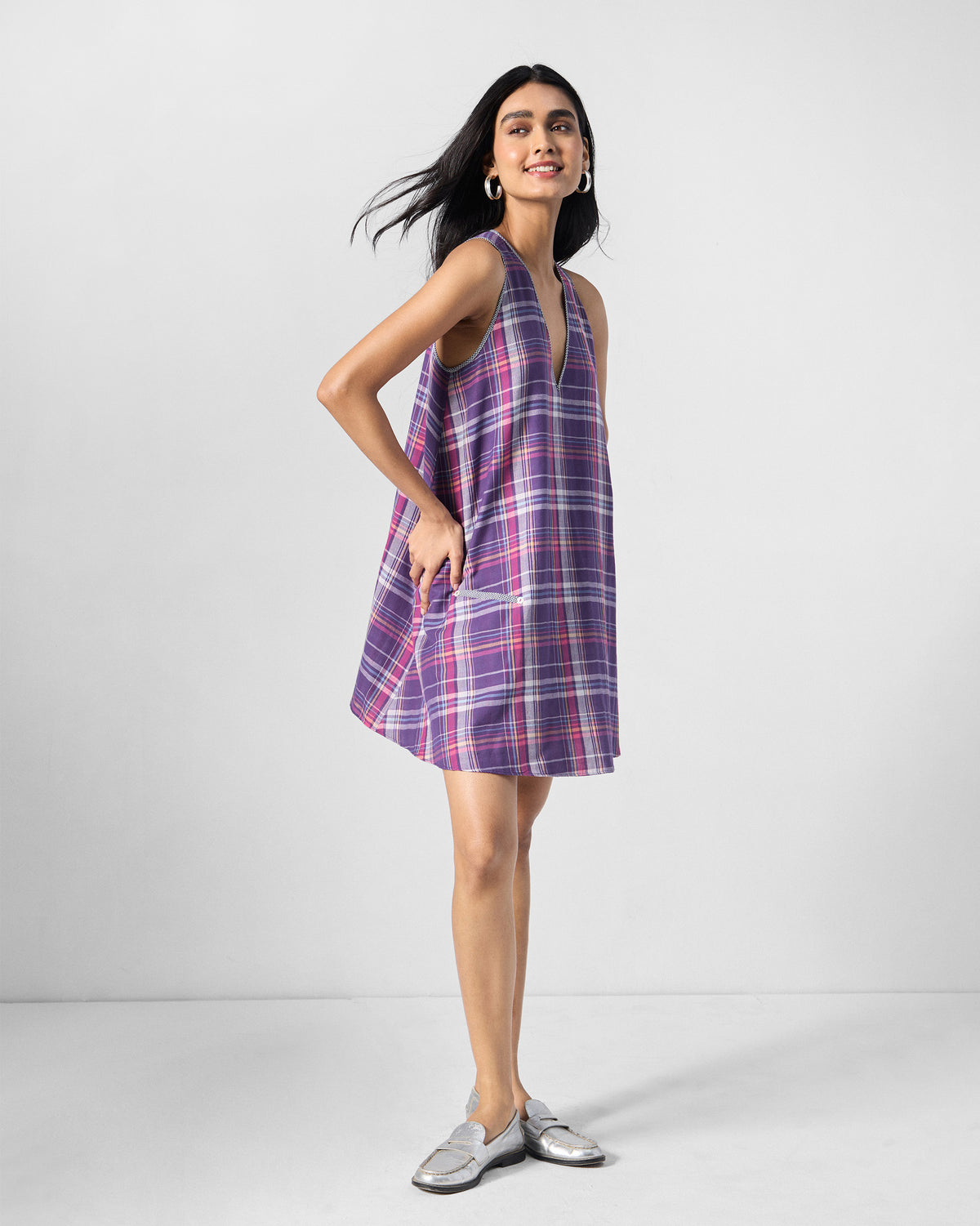Person wearing a purple check Daye dress with a piped side pocket.