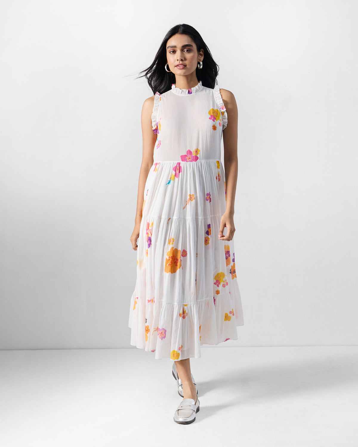Person wearing an ivory Reah dress with a tiered skirt and floral print.