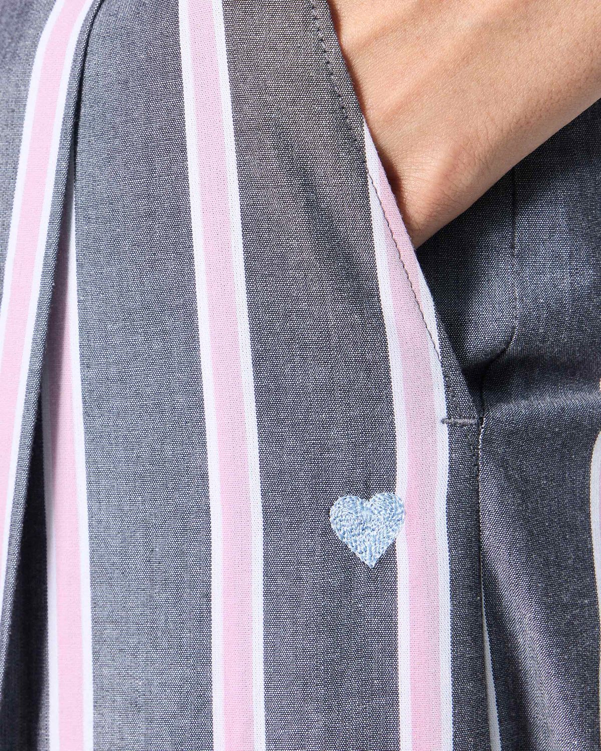 Close-up of a blue embroidered heart near the pocket of striped Row pants.