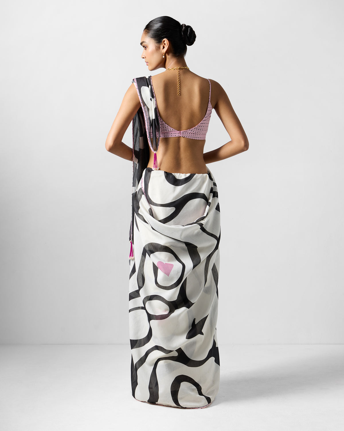 Back of a white and black Ella sari with pink tassels and a scoop-back blouse.