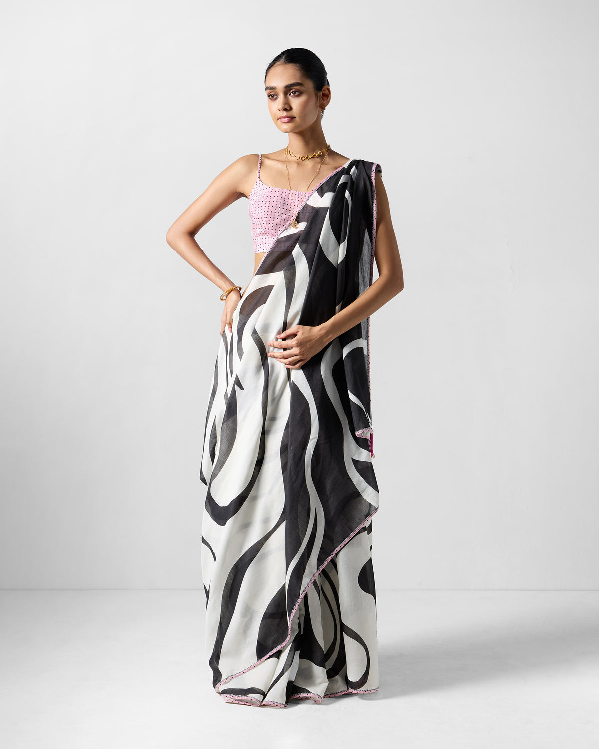 Person wearing a white and black Ella sari with pink edging and a check blouse.