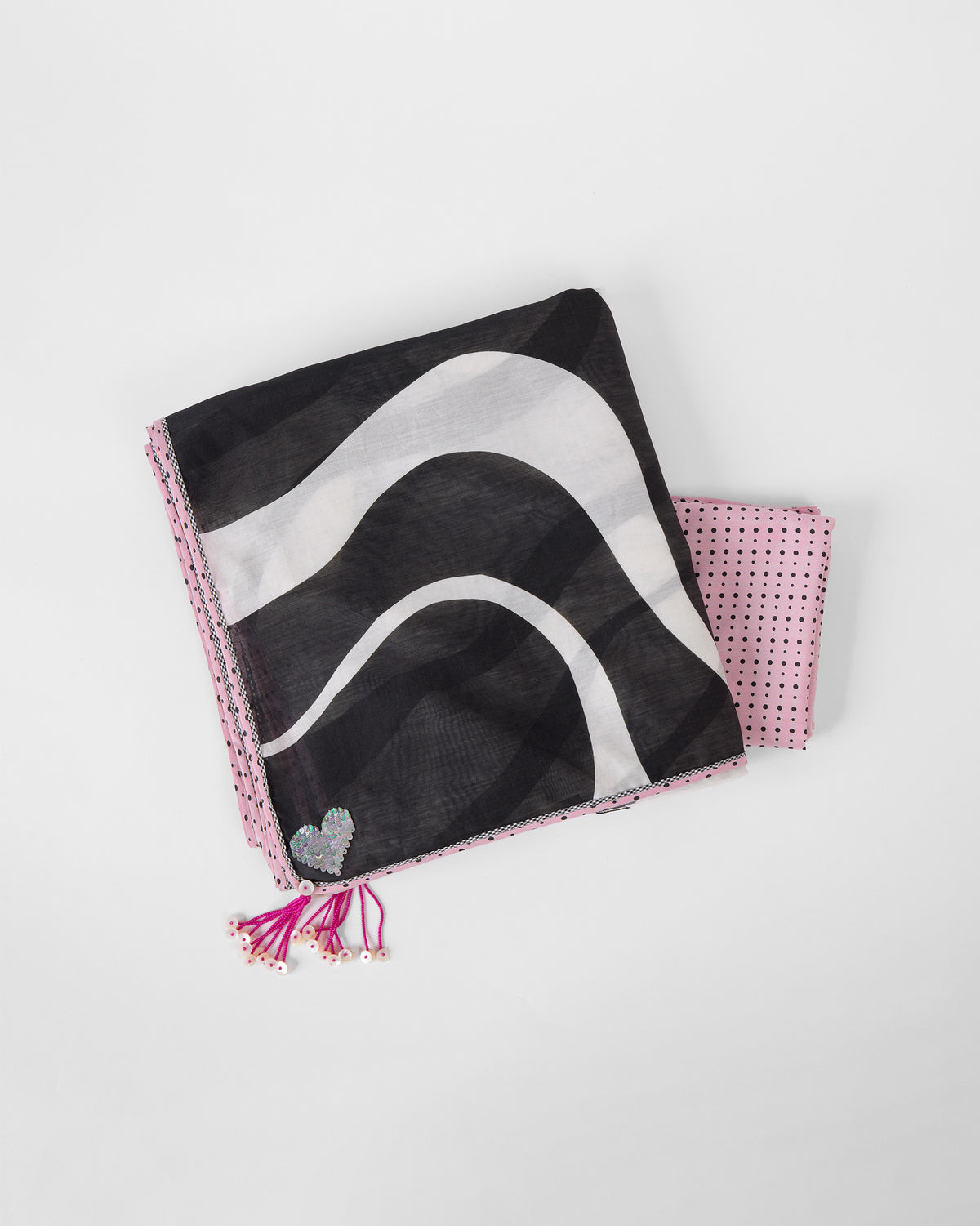 White and black printed Ella sari laid flat with a sequin heart and pink tassels.